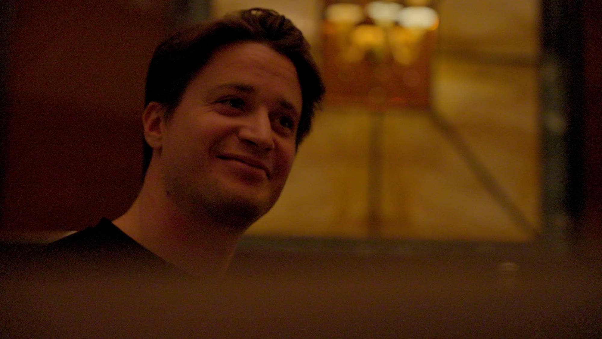 En mann ser skrått opp mot høyre og smiler