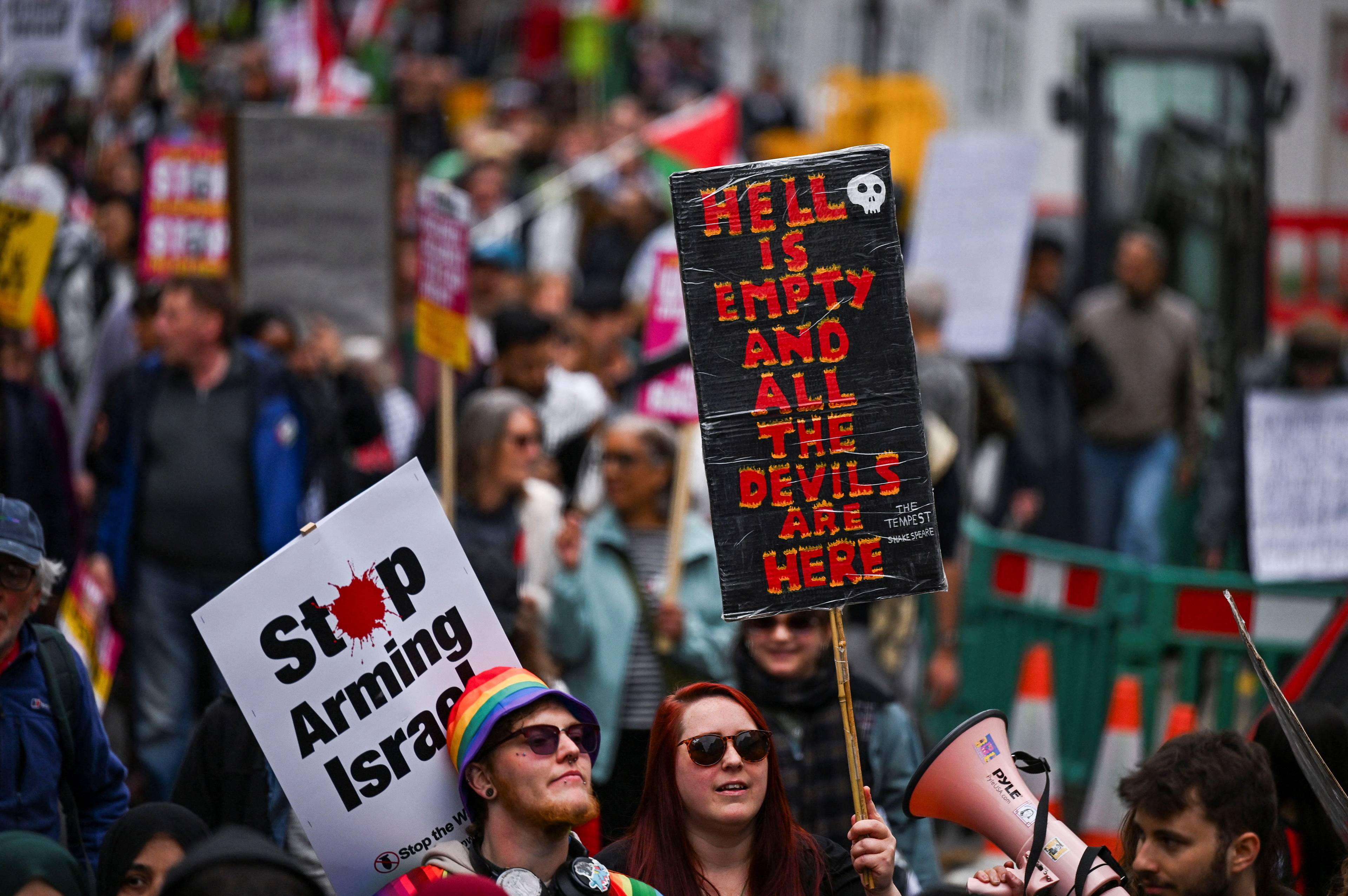 Folk med skilt i det pro-palestinske protesttoget. En dame holder et skilt hvor det står "Hell is empty and the devils are here".