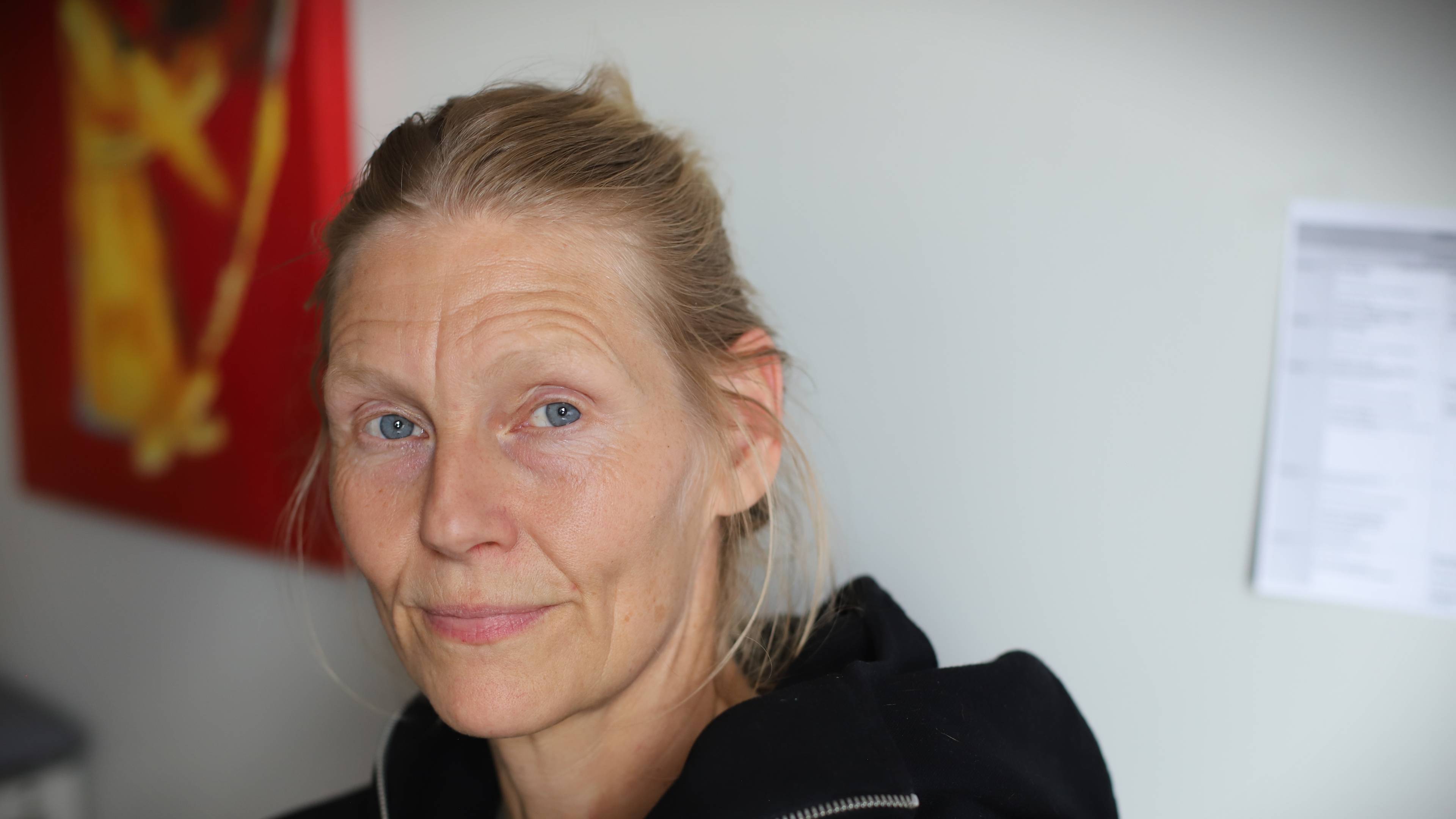 En kvinne med lyst hår satt i en knute ser i kamera.