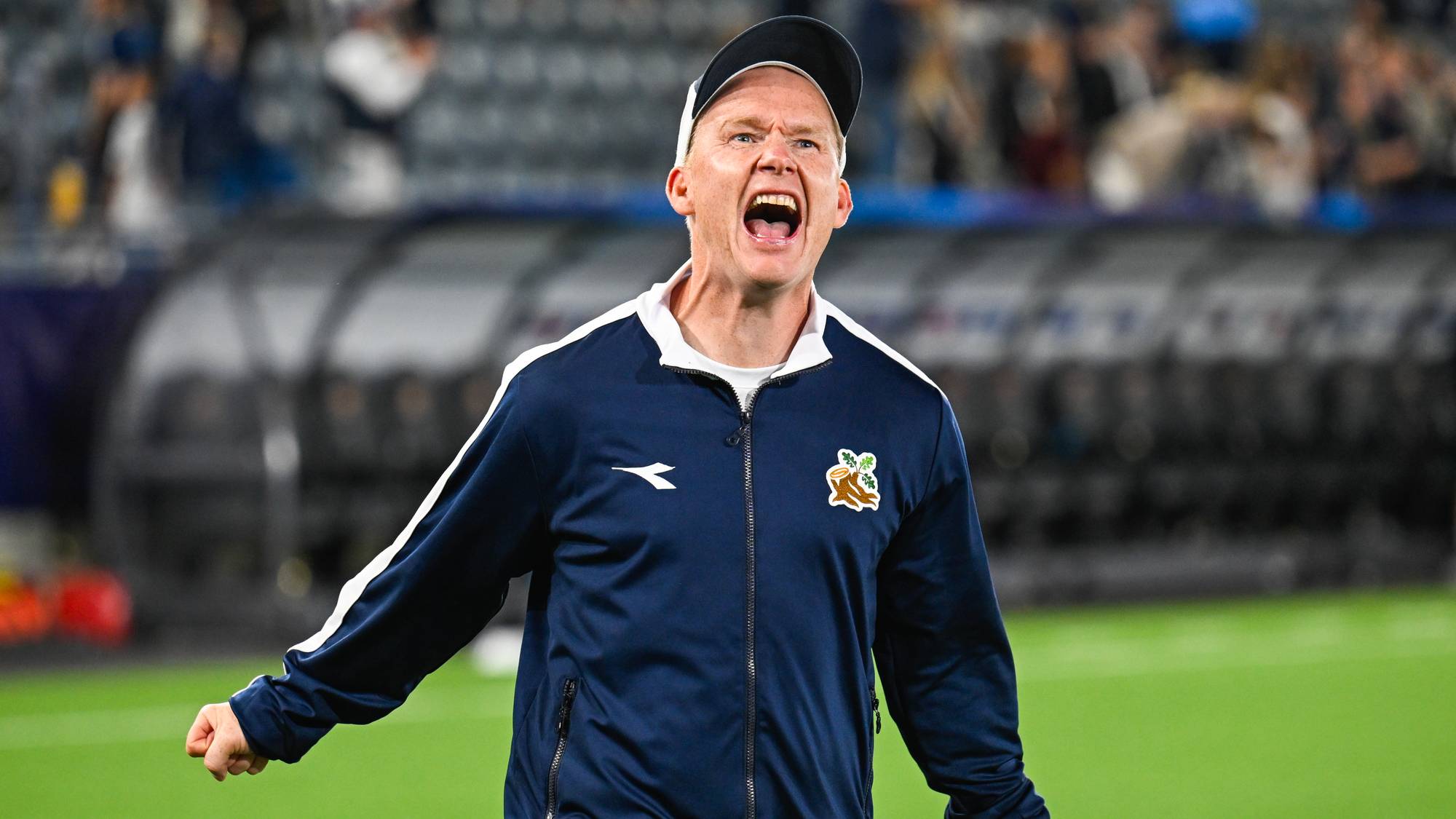 Fotballtrener roper med knyttede hender på sidelinjen under en fotballkamp. (Bildebeskrivelsen er laget av en KI-tjeneste)
