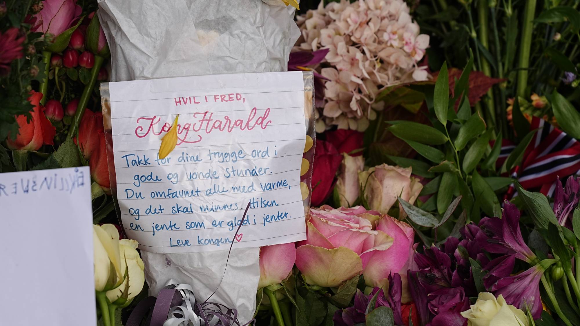 Blomsterhilsen med håndskrevet kort til Kong Harald lagt ned som markering. 