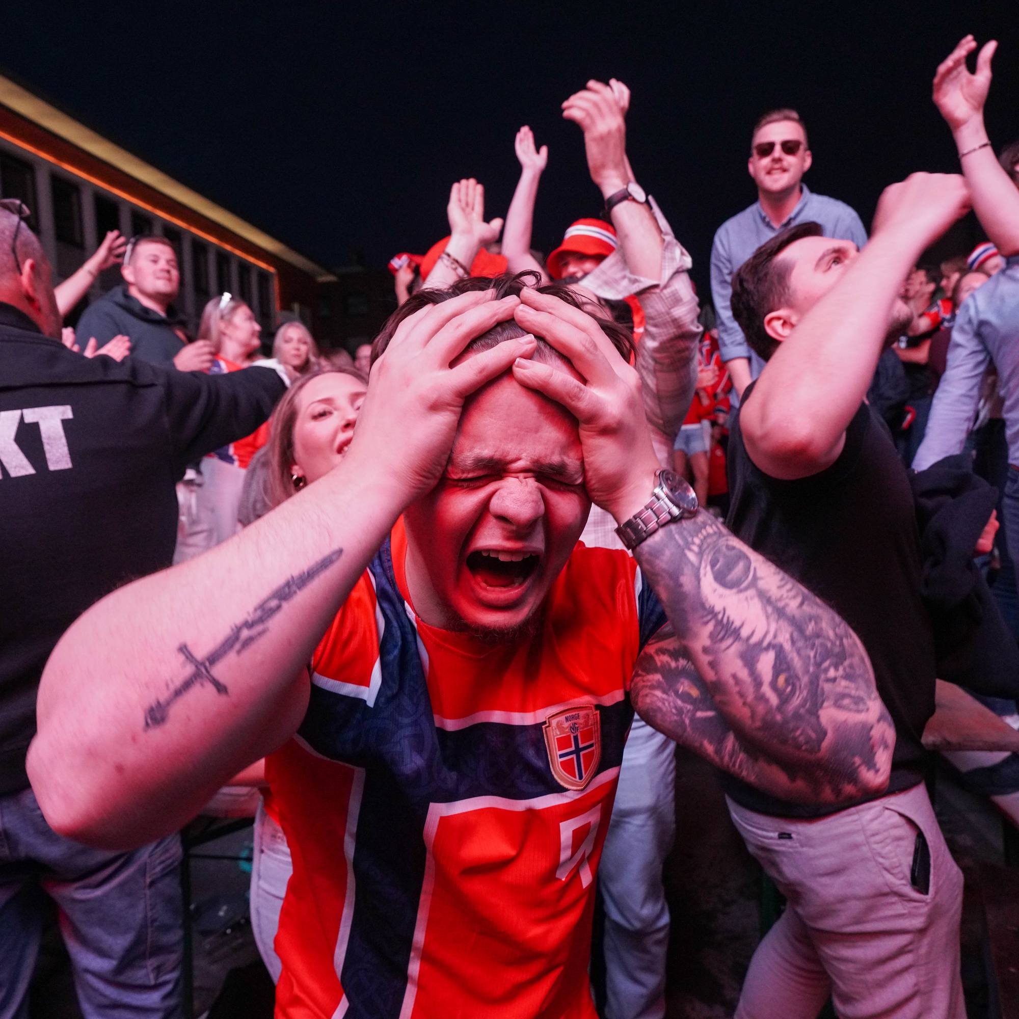 Fotballsupportere i Norge-drakter reagerer med sterke følelser under kamp. (Bildebeskrivelsen er laget av en KI-tjeneste)