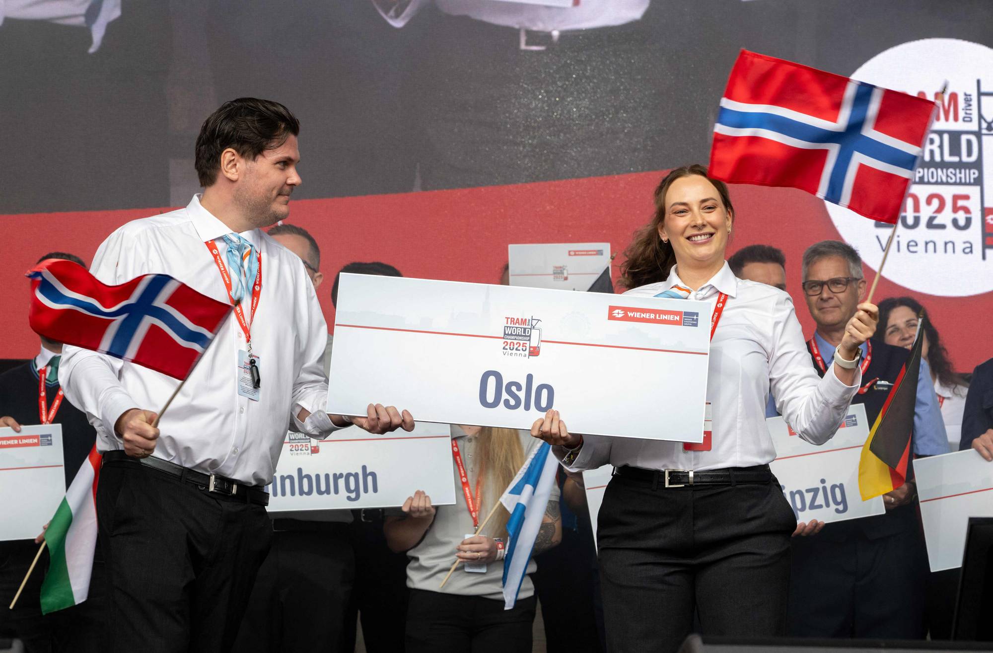 To personer holder et skilt med teksten Oslo og norske flagg under Tram World Championship. (Bildebeskrivelsen er laget av en KI-tjeneste)