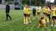 Paul S. Amundsen / NTB Fotballspillere i gule drakter står på en gressbane. En person i svart jakke og bukser går forbi. Laget ser ut til å samles på banen. (Bildebeskrivelsen er laget av en KI-tjeneste)
