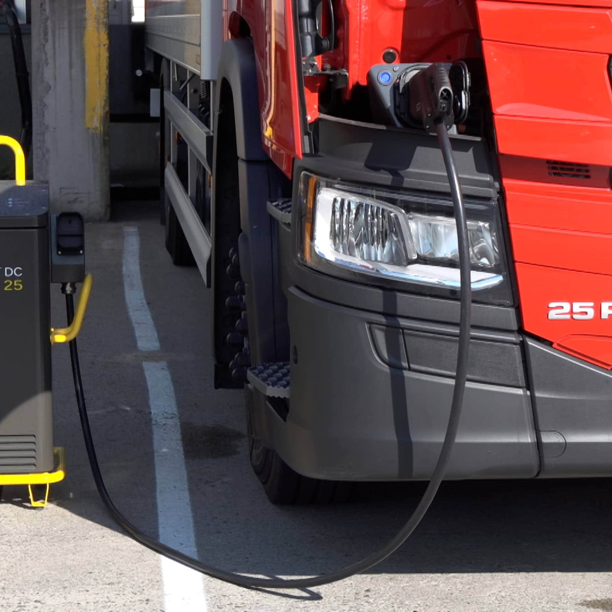 En rød elektrisk lastebil lades av en flyttbar lader fra Heliox. (Bildebeskrivelsen er laget av en KI-tjeneste)