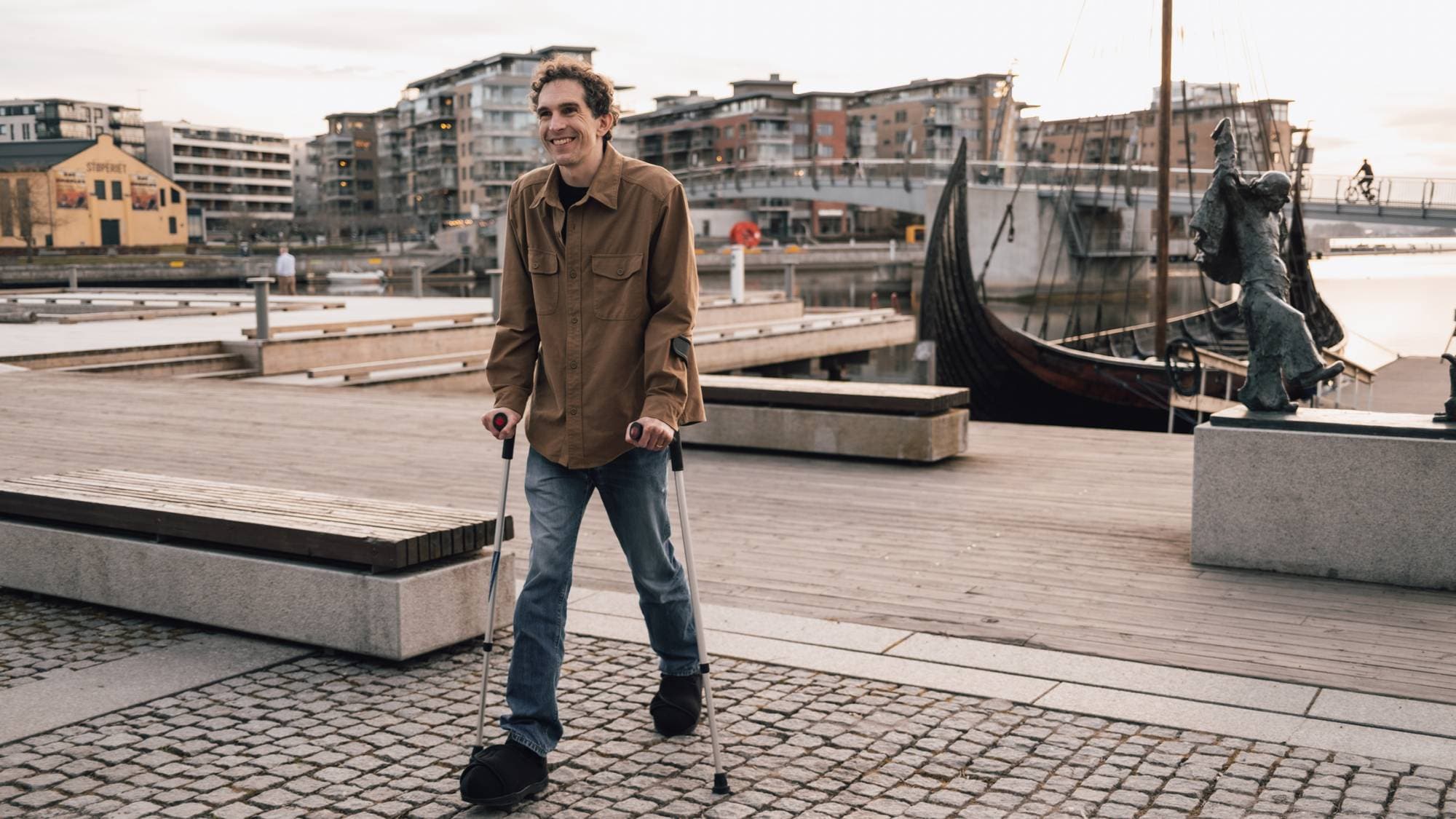 En person som går på en mursteinsgangvei med krykker (Bildebeskrivelsen er laget av en KI-tjeneste)