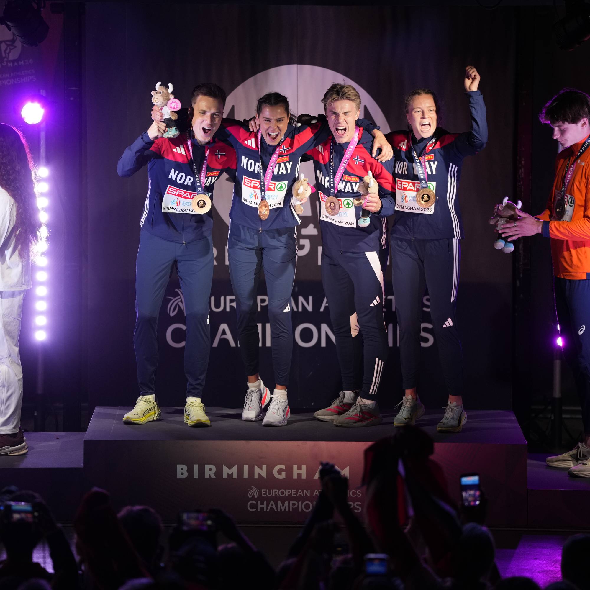 Norske utøvere jubler på seierspallen etter medaljeutdeling i friidretts-EM. (Bildebeskrivelsen er laget av en KI-tjeneste)