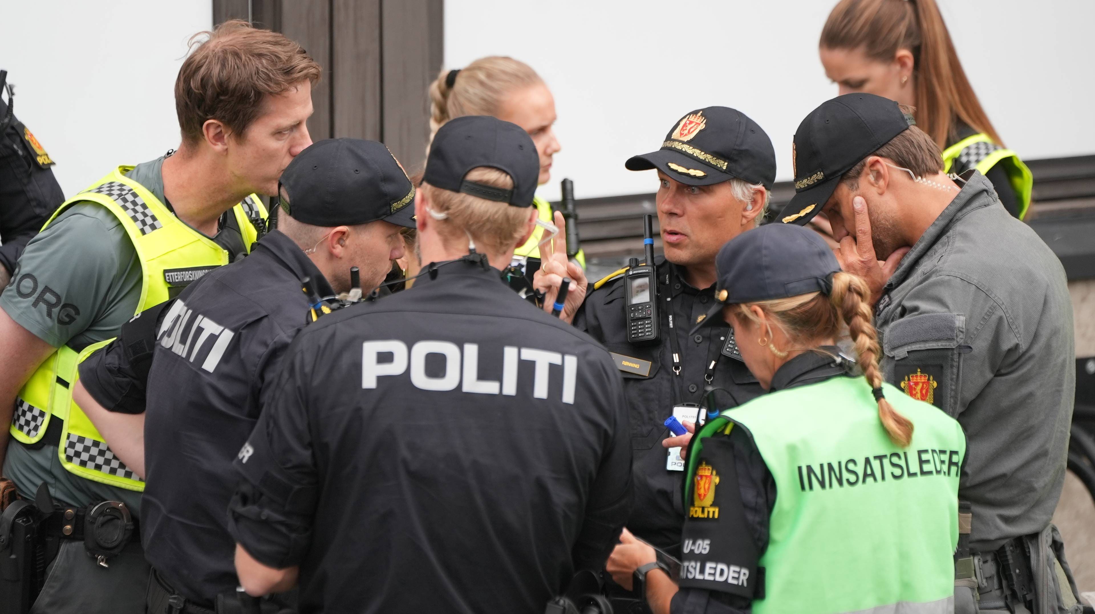 Politibetjenter i uniform samlet til briefing utendørs. Innsatsleder står i sentrum. (Bildebeskrivelsen er laget av en KI-tjeneste)