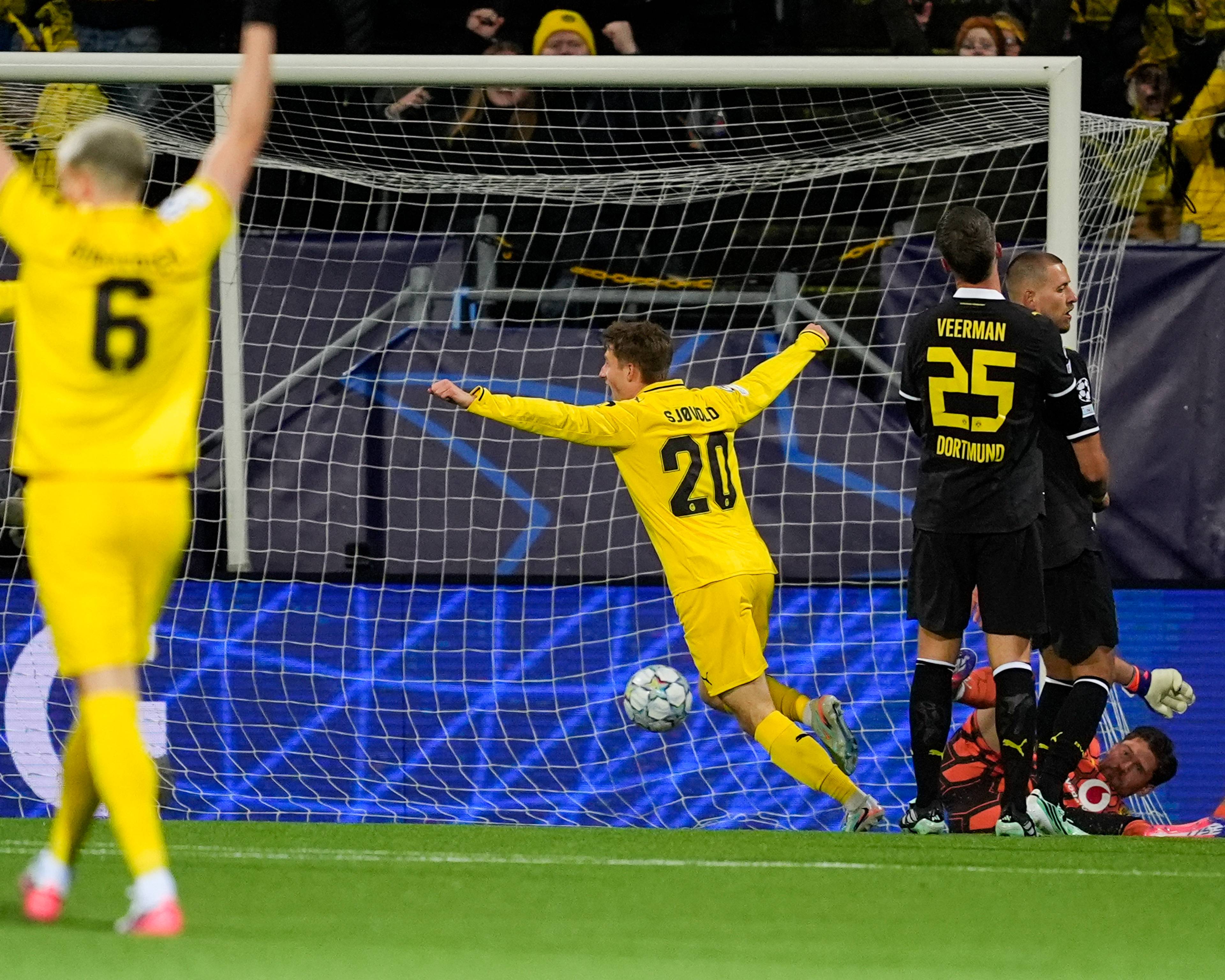 Fotballspiller jubler etter scoring foran et mål mens lagkamerater og motstandere ser på. (Bildebeskrivelsen er laget av en KI-tjeneste)