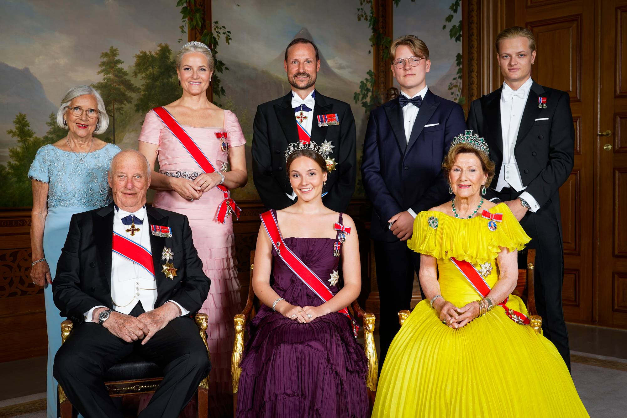 Det norske kongefamilien er samlet på et offisielt bilde. Kong Harald V sitter i forgrunnen, flankert av dronning Sonja og kronprinsfamilien. (Bildebeskrivelsen er laget av en KI-tjeneste)