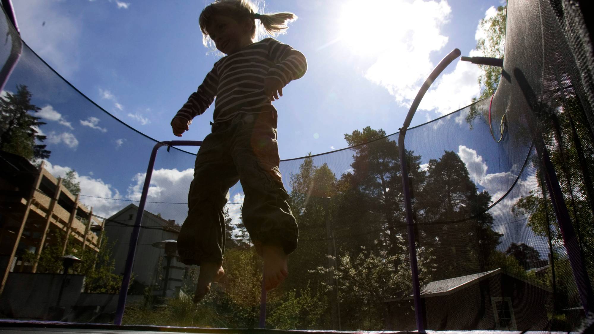 Liten jente hopper på trampoline med sikkerhetsnett