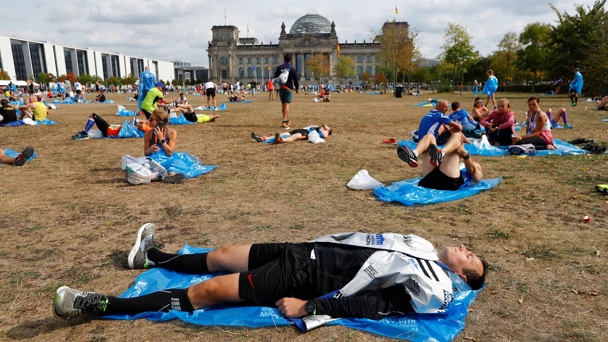 Folk ligger utslått på bakken utafor Riksdagen i Berlin etter å ha deltatt i Berlin maraton.