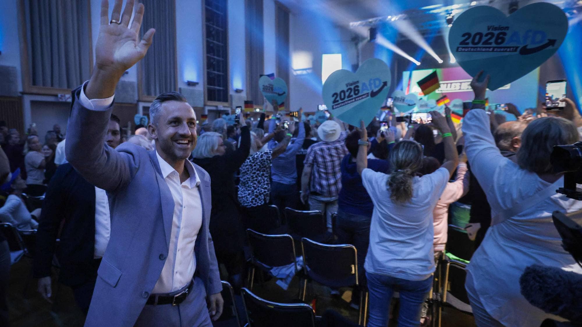 Ulrich Siegmund vinker til publikum på et politisk arrangement for partiet AfD. (Bildebeskrivelsen er laget av en KI-tjeneste)