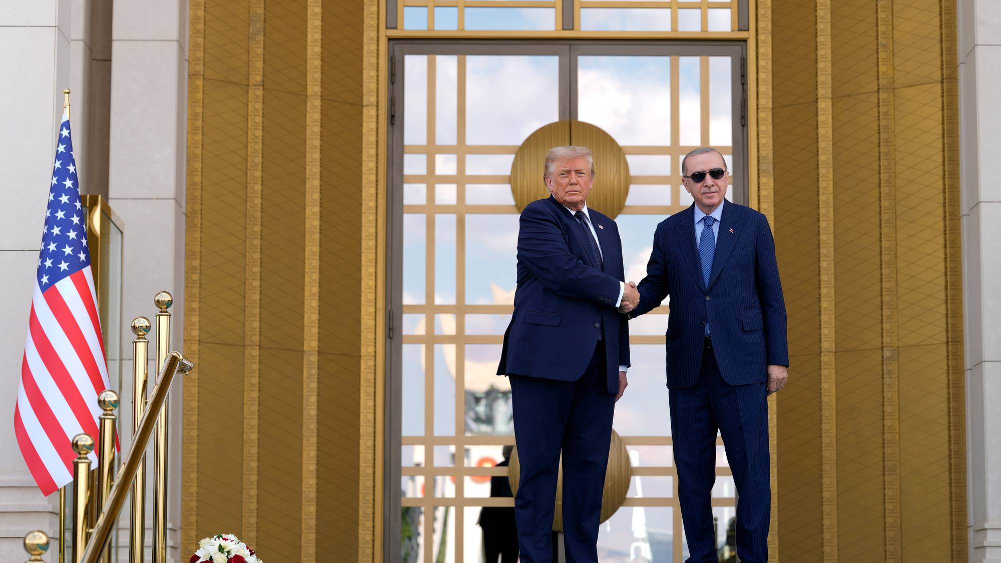 Donald Trump og Recep Tayyip Erdogan håndhilser foran en bygning med et amerikansk flagg ved siden. 