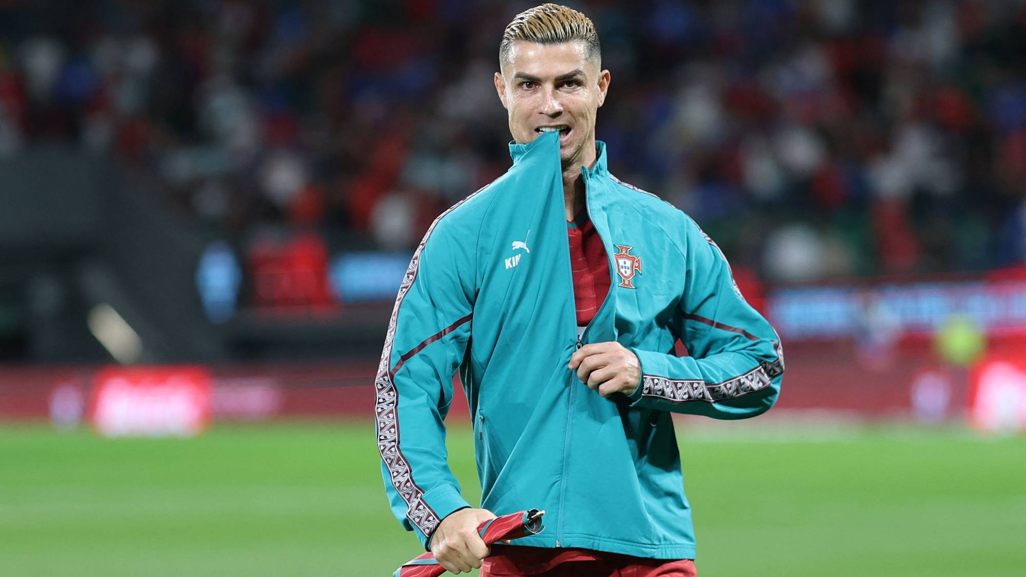 Cristiano Ronaldo i Portugal-drakt med en jakke mot ansiktet på en fotballbane. (Bildebeskrivelsen er laget av en KI-tjeneste)