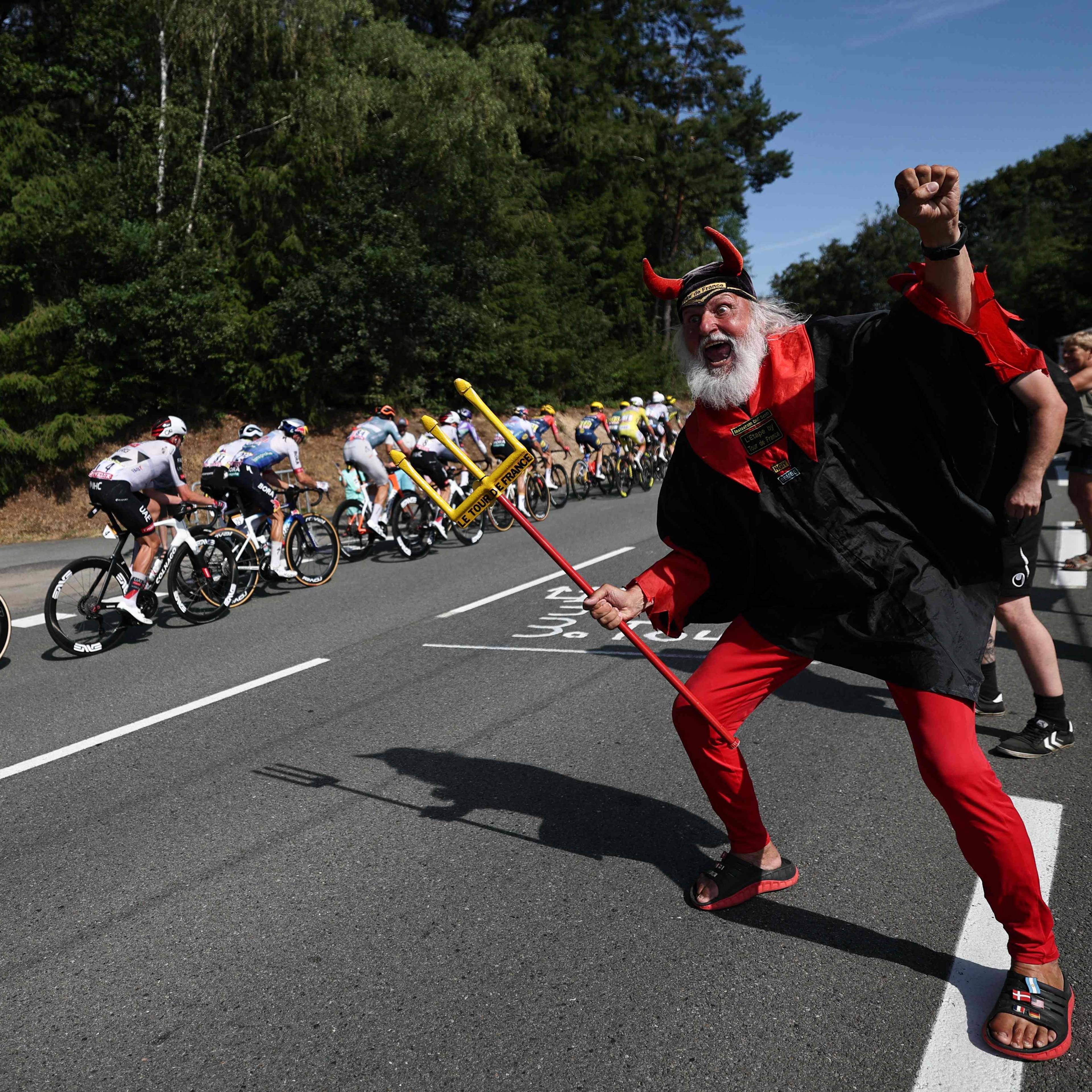 En mann utkledd som djevelen heier på syklister i Tour de France. (Bildebeskrivelsen er laget av en KI-tjeneste)