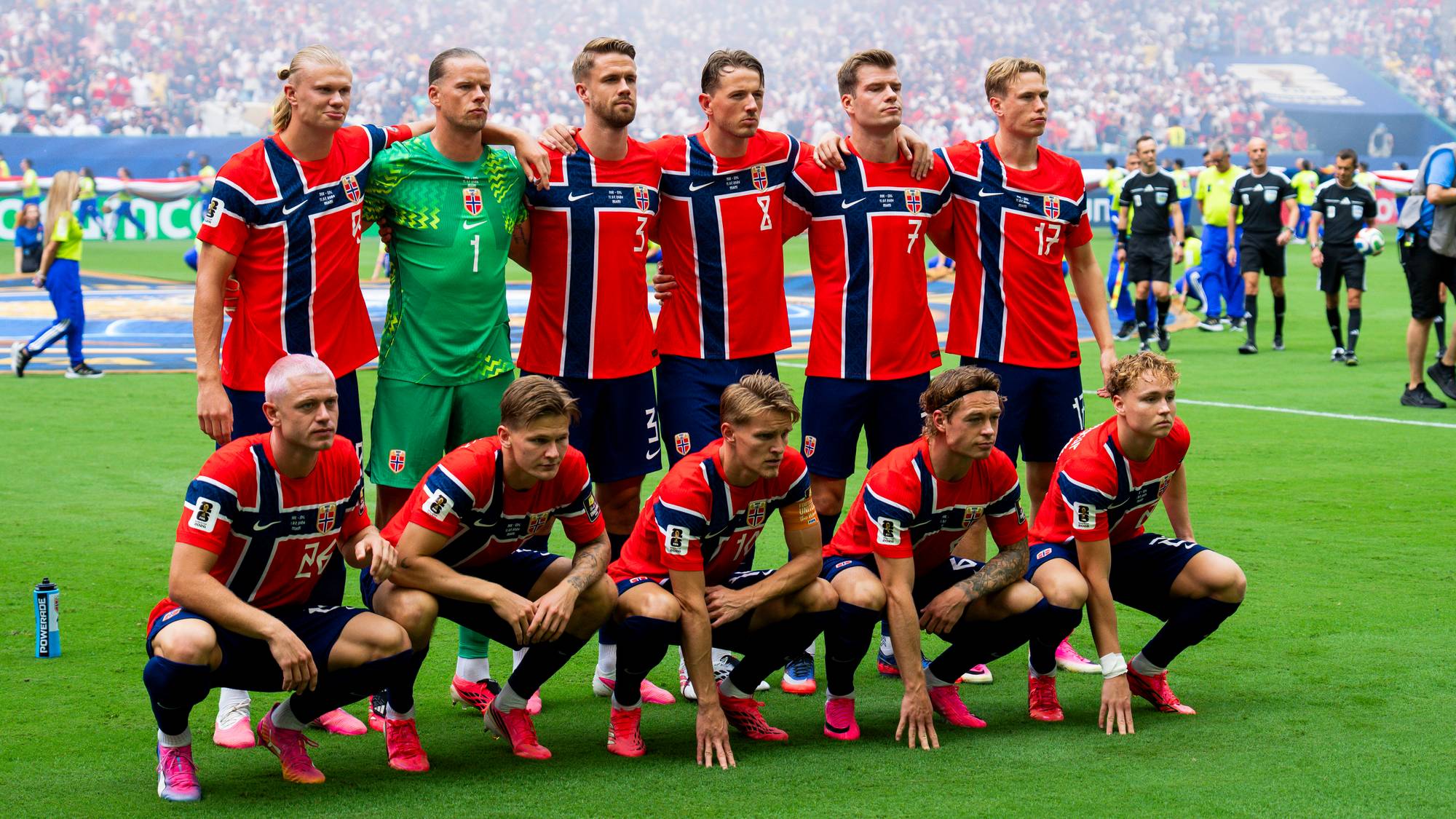 Fotballandslaget poserer på banen før avspark mot England. Alle i røde, hvite og blå drakter, keeperen i grønn. I bakgrunnen er en fullsatt stadion.