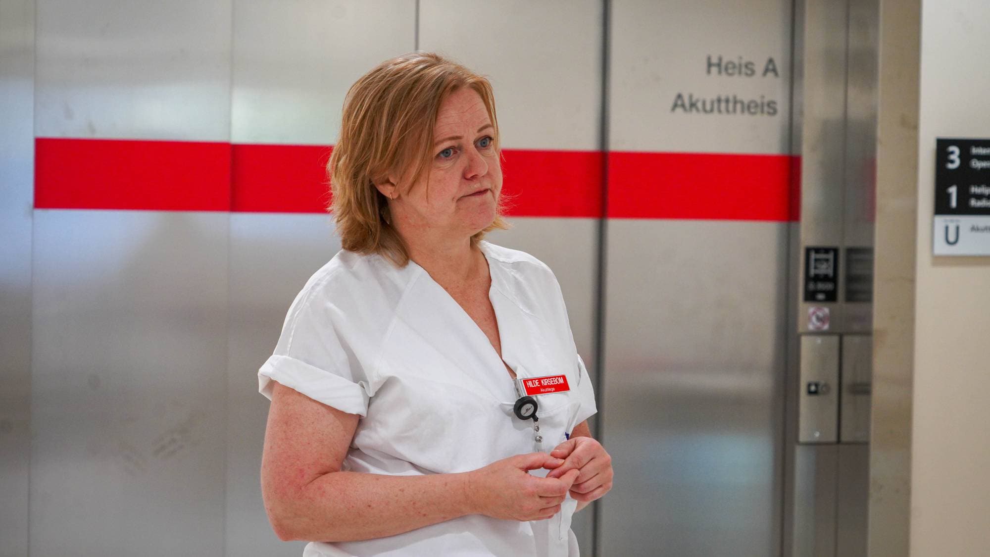 kvinne i hvit uniform foran en heis av stål