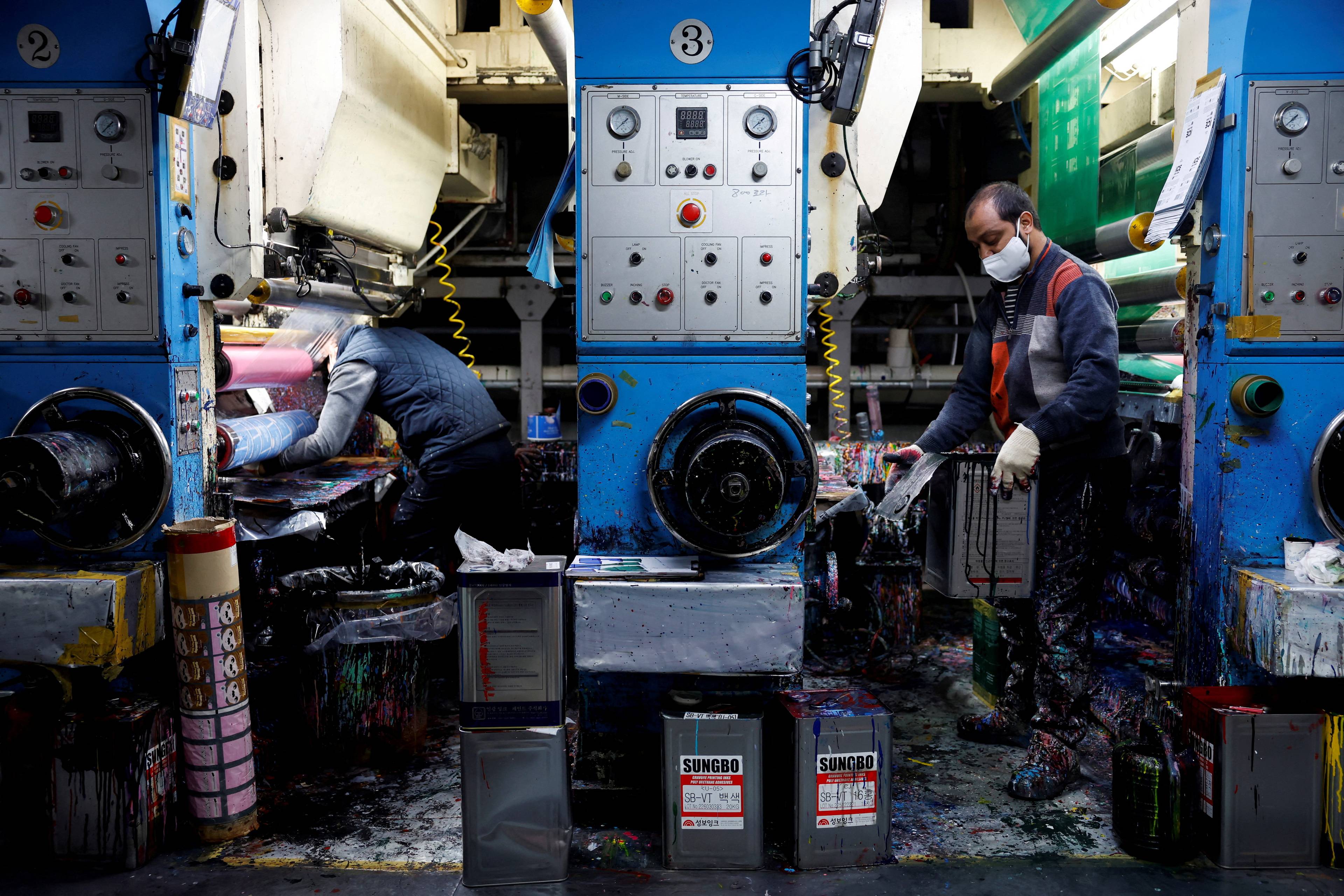 To arbeidere jobber med store trykkemaskiner