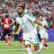 KYLIE GRAHAM / REUTERS,NTB Riyad Mahrez feirer mål i Algerie-drakt på en fotballstadion med publikum i bakgrunnen. (Bildebeskrivelsen er laget av en KI-tjeneste)