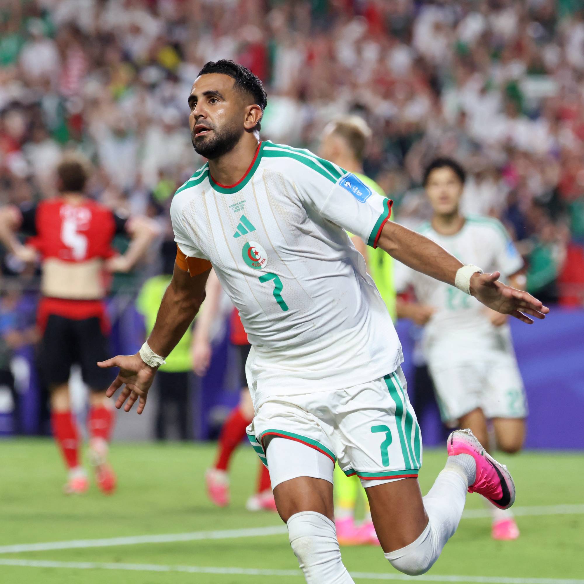 Riyad Mahrez feirer mål i Algerie-drakt på en fotballstadion med publikum i bakgrunnen. (Bildebeskrivelsen er laget av en KI-tjeneste)