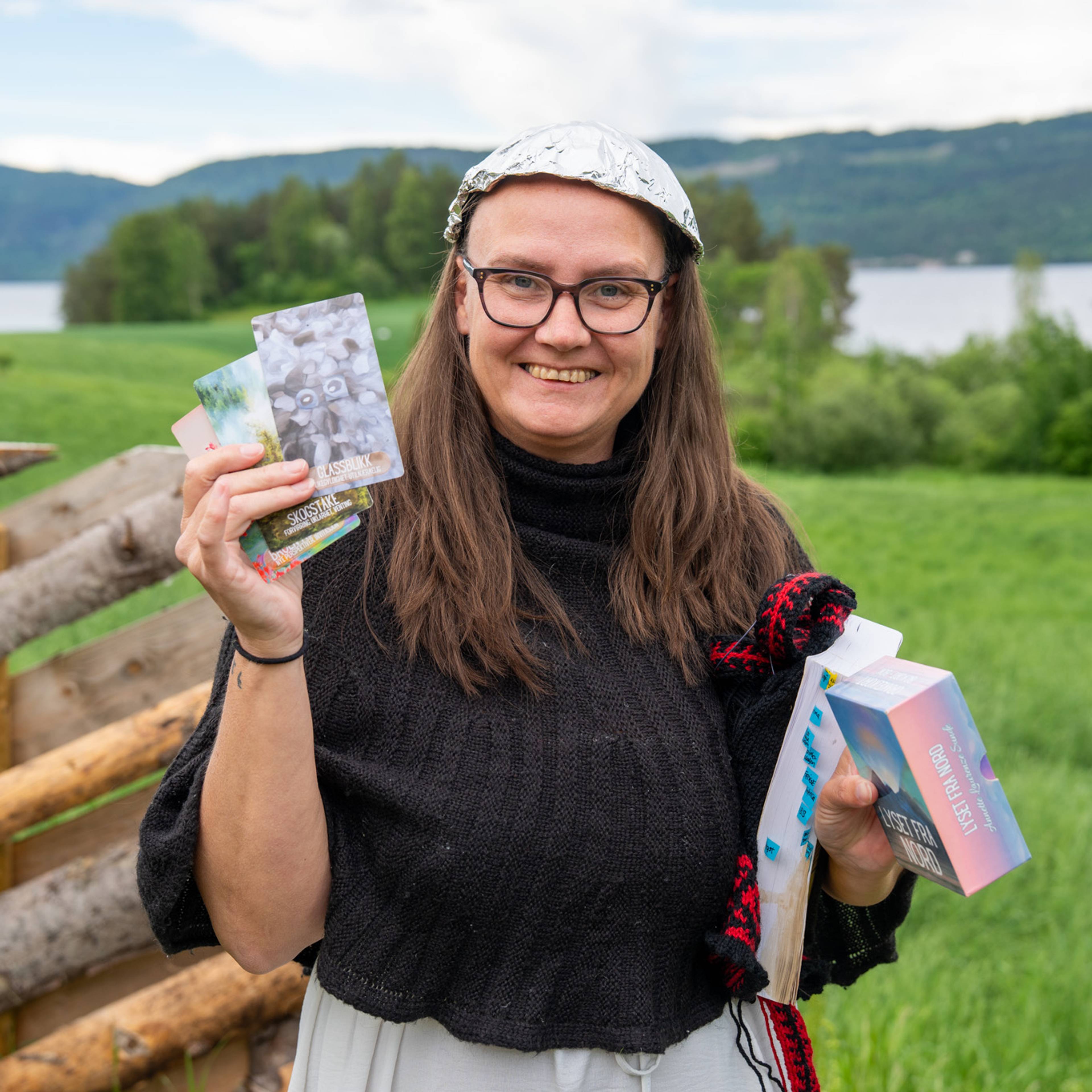Lena Nordstrøm smiler med tarotkort i henda