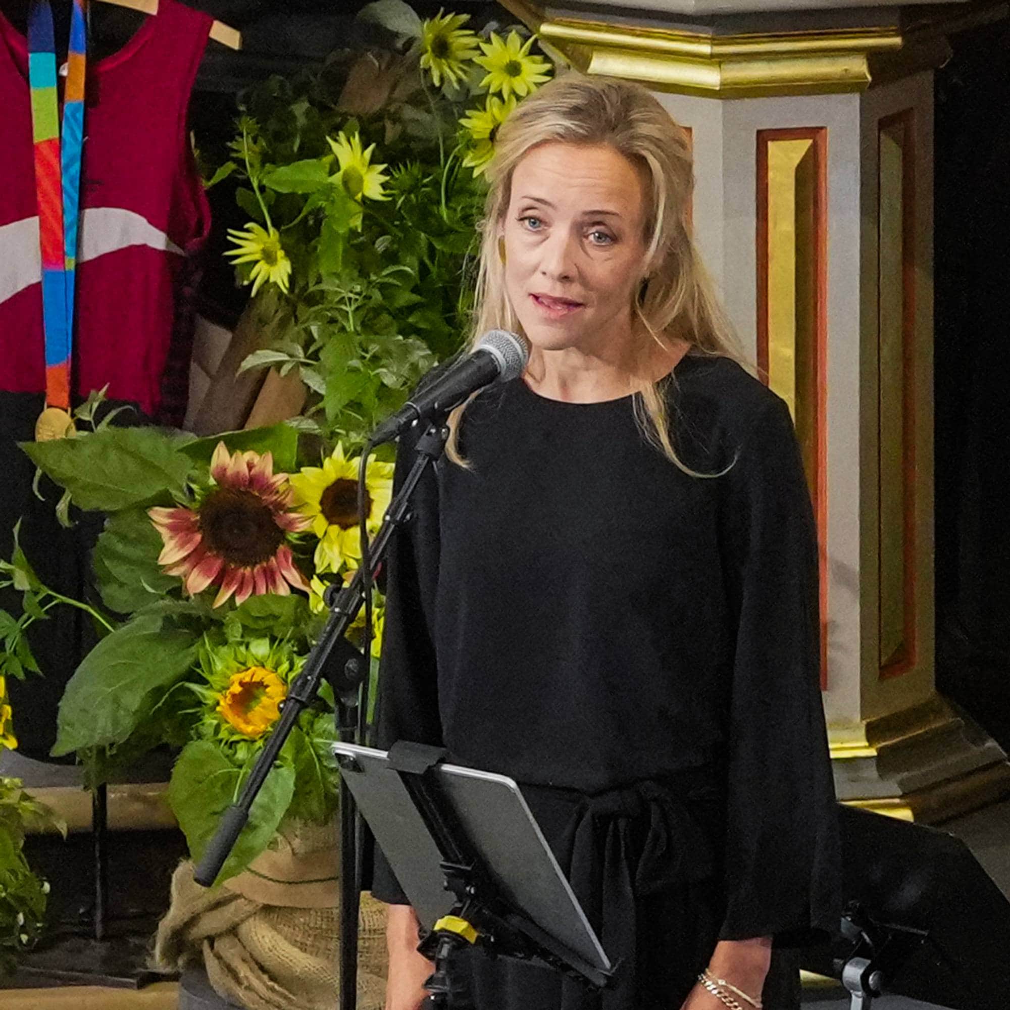 En kvinne synger og en annen spiller saksofon under en begravelse i en kirke.