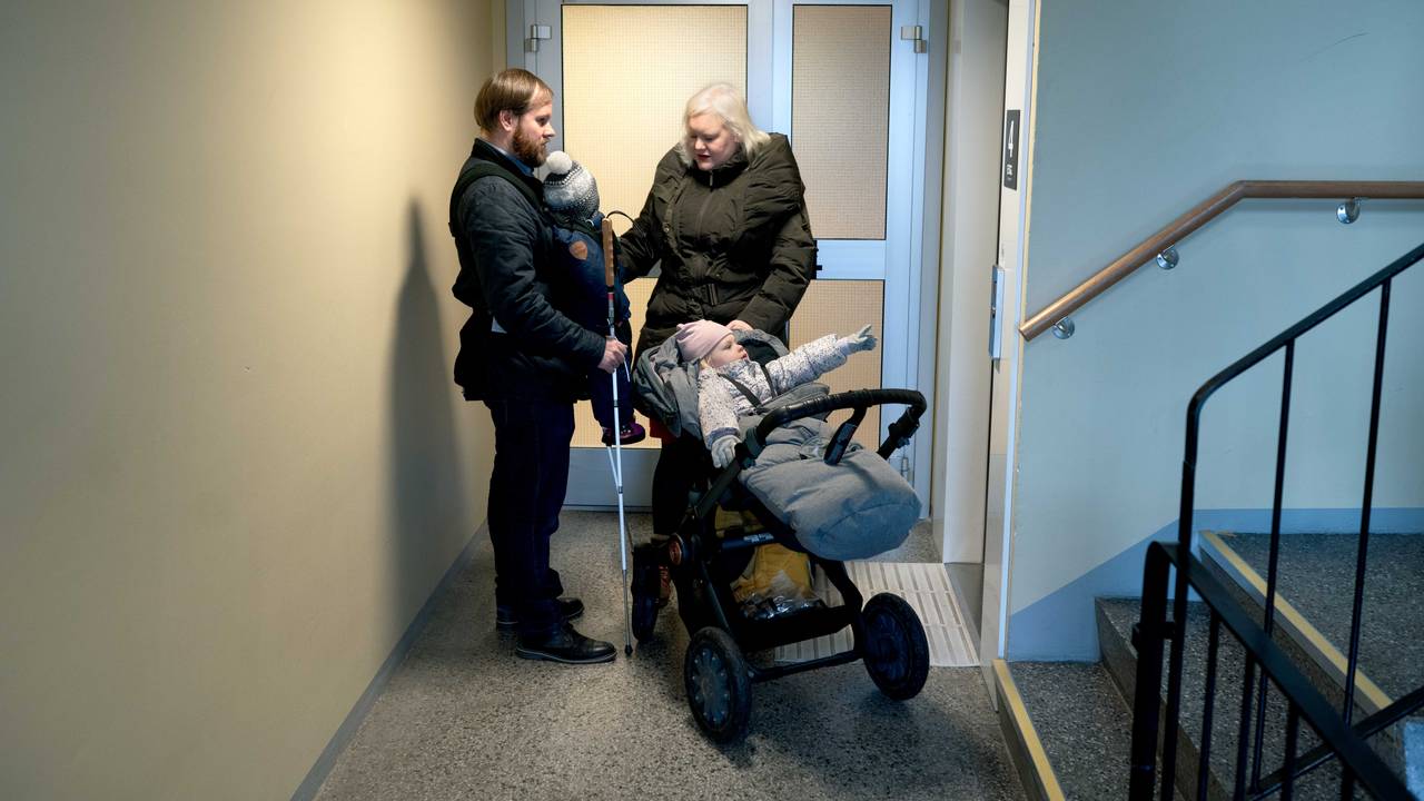 Familien er ute i gangen, og klare til å dra ut. Bjørn Roger har sønnen Tancred festet på magen, Nanna er i barnevogna og Ida-Martine står ved siden av. Begge foreldrene har med blindestokker.
