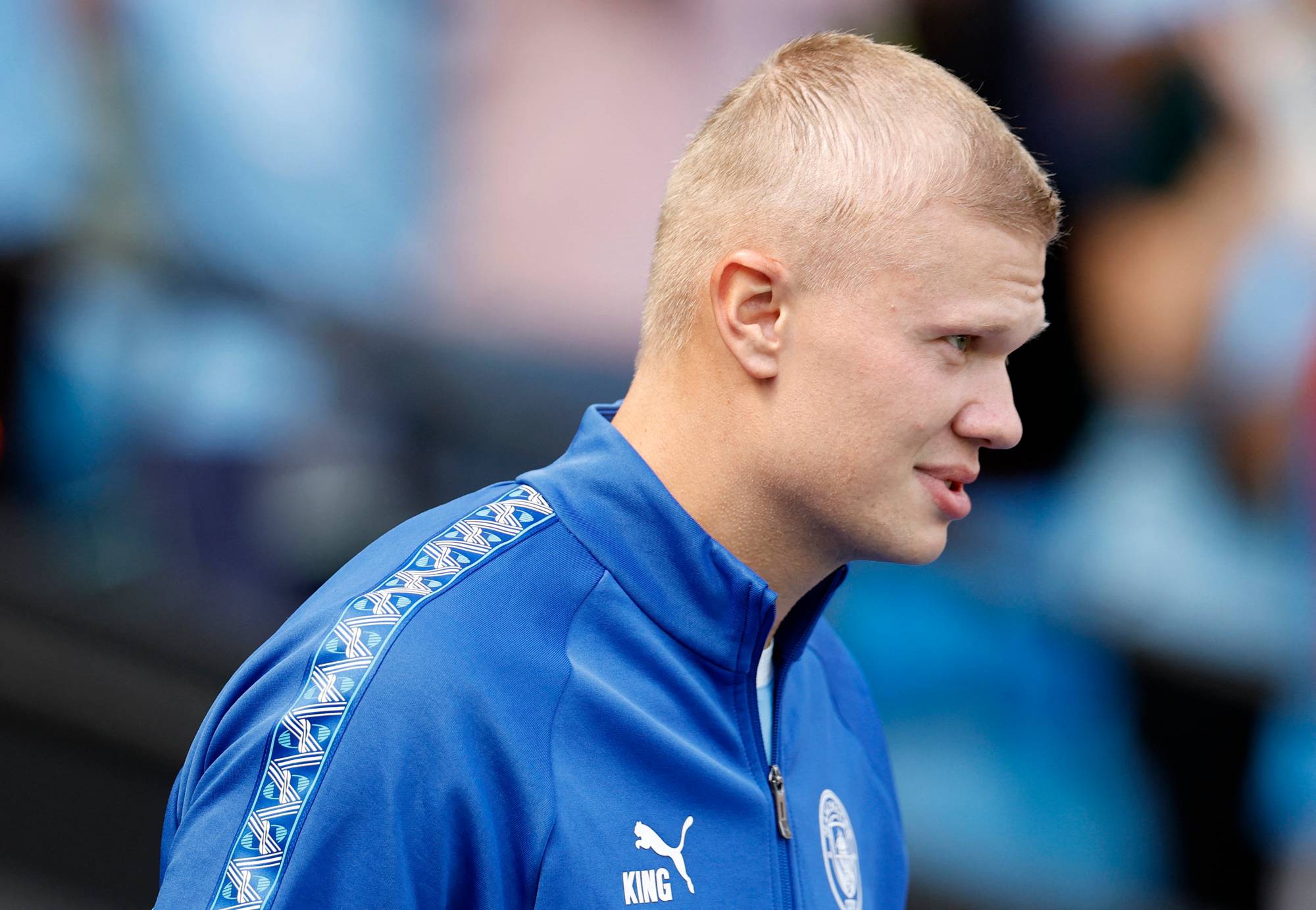 Erling Braut Haaland med kortklipt hår i en blå treningsjakke fra Puma. (Bildebeskrivelsen er laget av en KI-tjeneste)
