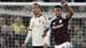 Dave Shopland / AP,NTB Fotballspiller feirer et mål. En annen spiller ser på. Kampen foregår på en gressbane. Tilskuere er synlige i bakgrunnen. (Bildebeskrivelsen er laget av en KI-tjeneste)