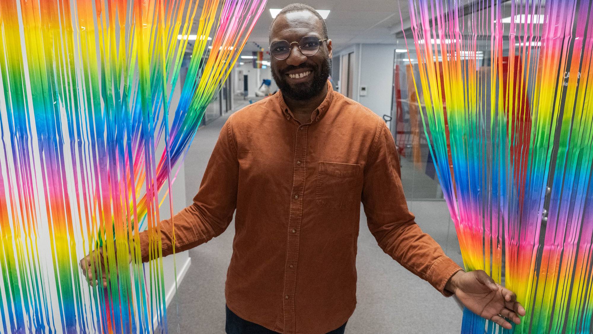 Stephen Adom tar et pride-forheng til side mens han smiler stort