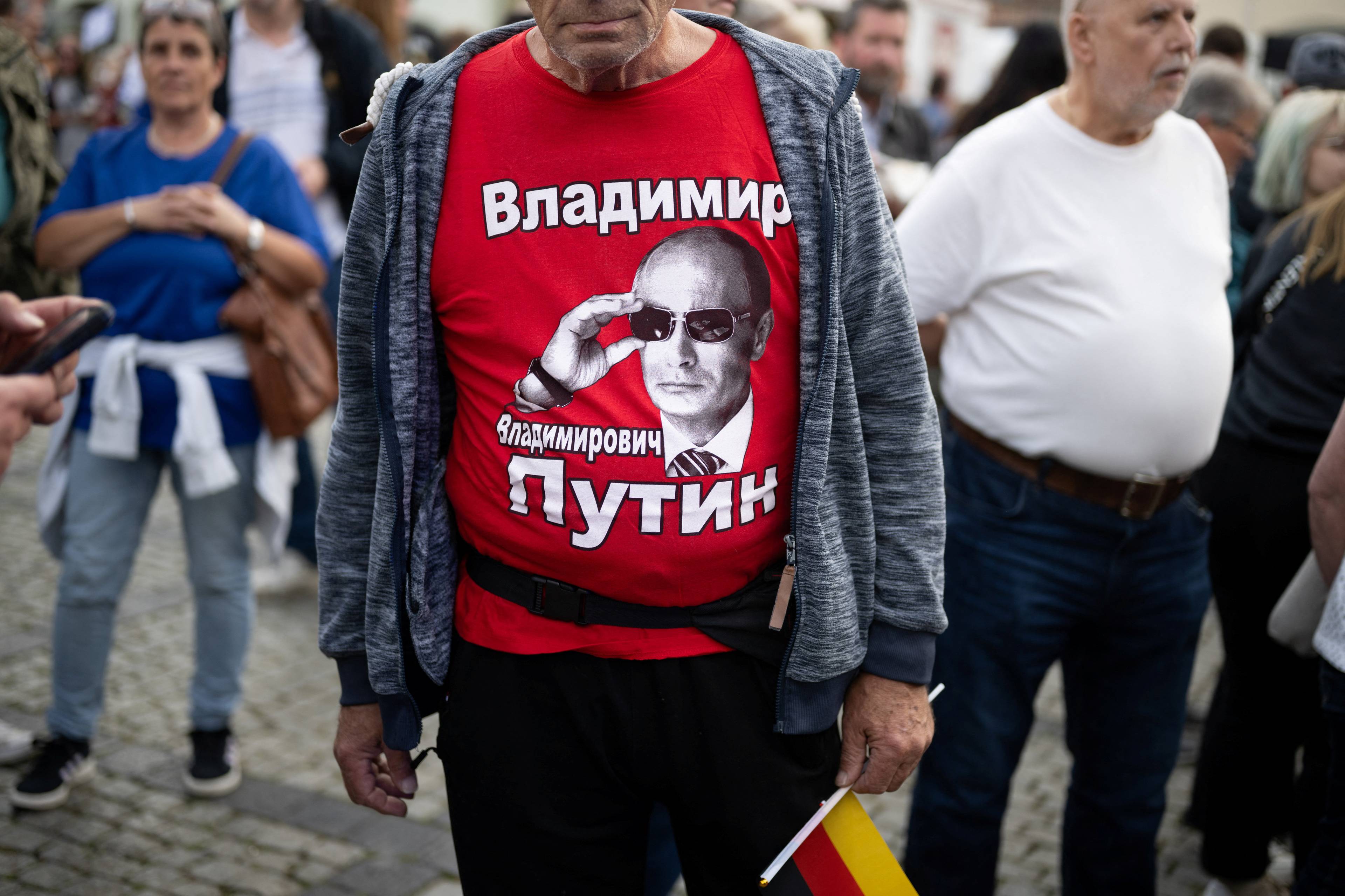 Person med rød t-skjorte med bilde av Vladimir Putin i en folkemengde.