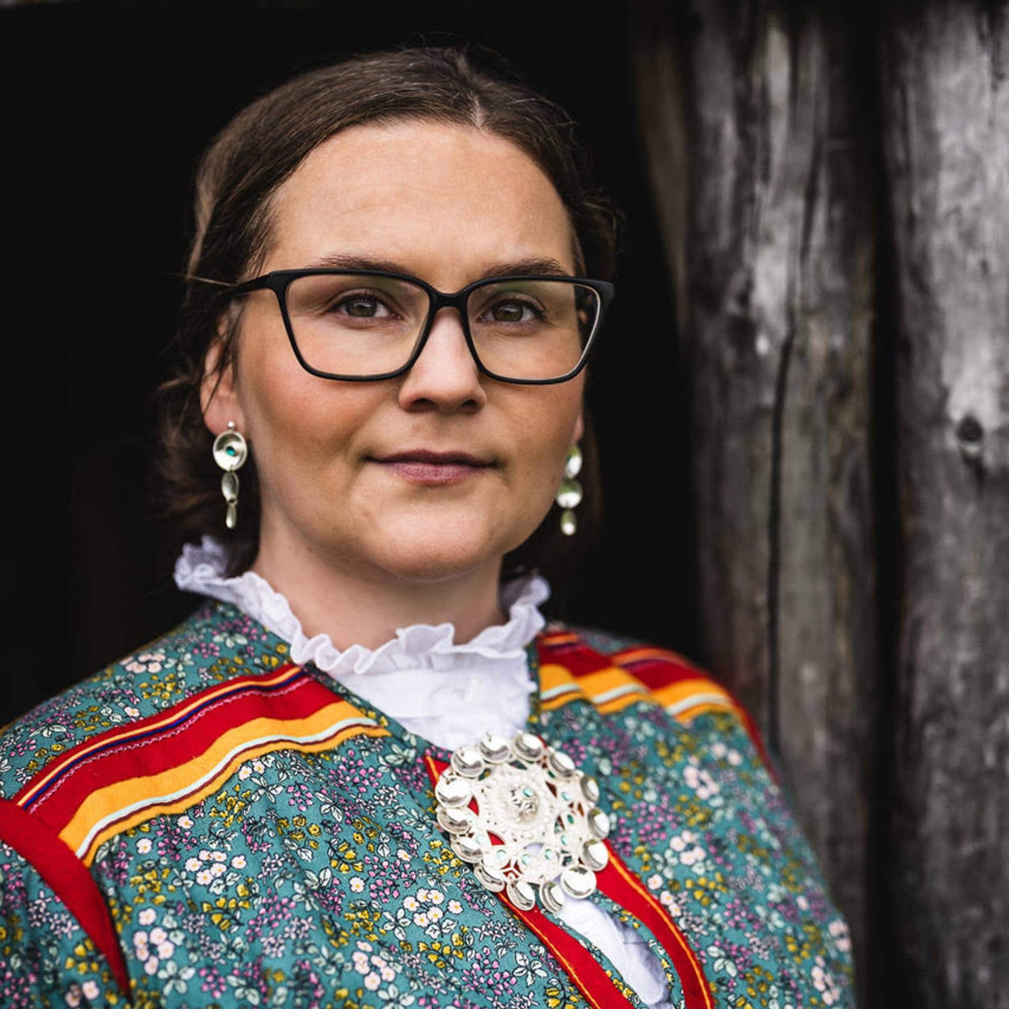 En kvinne med samekofte som ser rett i kamera.