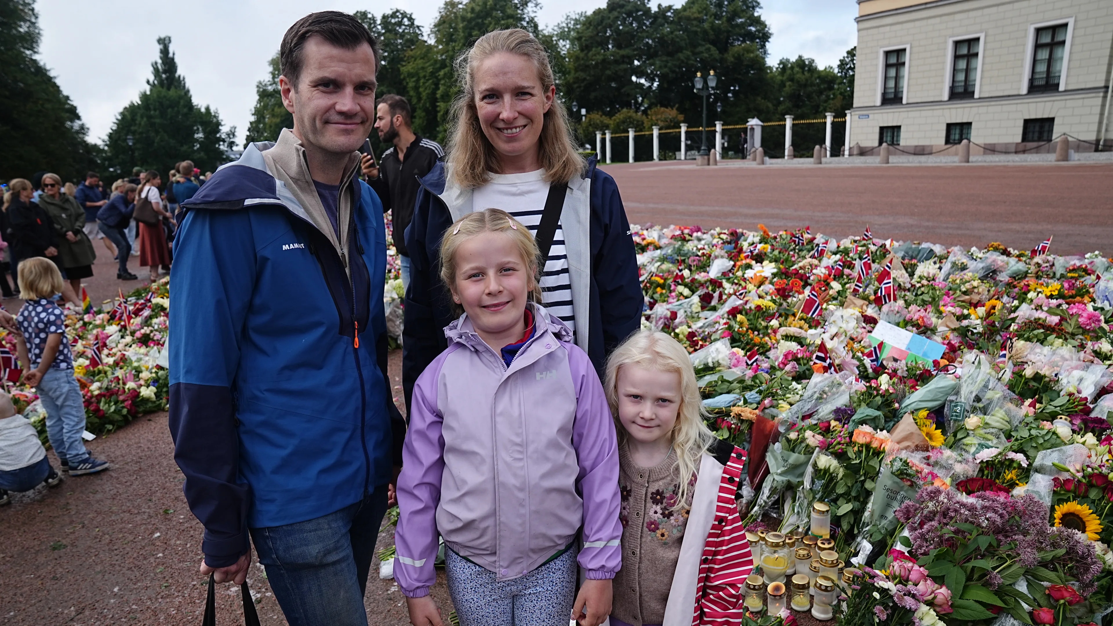 Familie foran blomsterhavet ved Slottet etter kong Haralds bortgang.