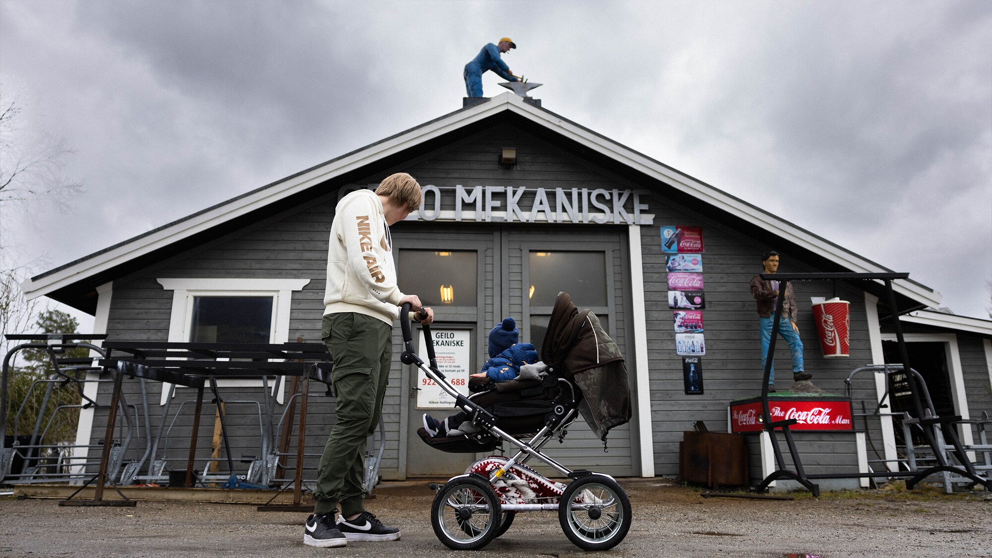 Bilde av Kjetil sammen med sønnen i en barnevogn foran Geilo mekaniske. 