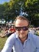 Privat / NRK Mann i lyseblå skjorte og solbriller tar bilde av seg selv i en park med publikum i bakgrunnen. (Bildebeskrivelsen er laget av en KI-tjeneste)