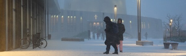 Snøvær og folk foran Nordlyskatedralen Alta kirke