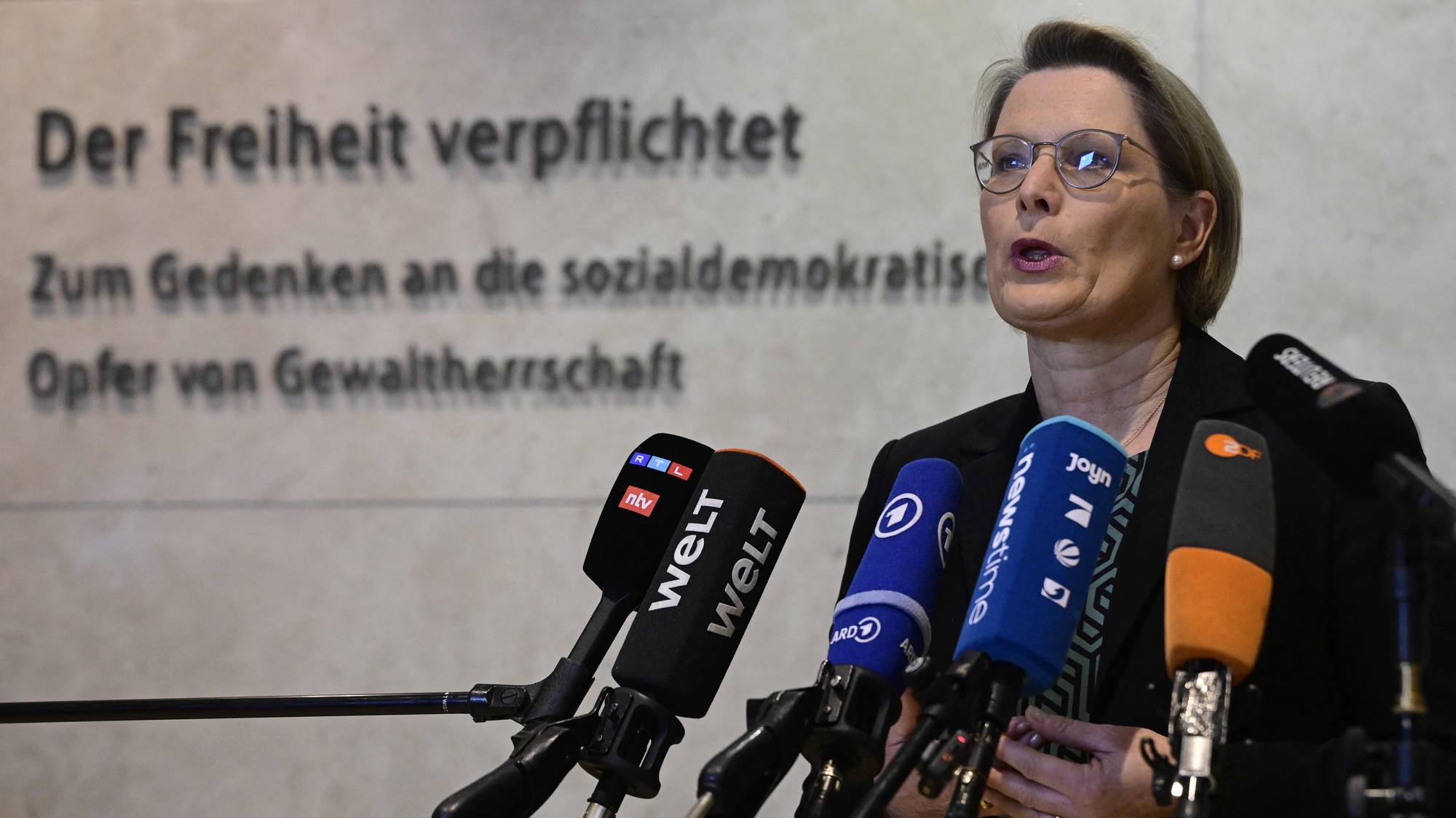Den tyske justisministeren, med halvlangt hår og briller, snakker bak en rekke med mikrofoner.