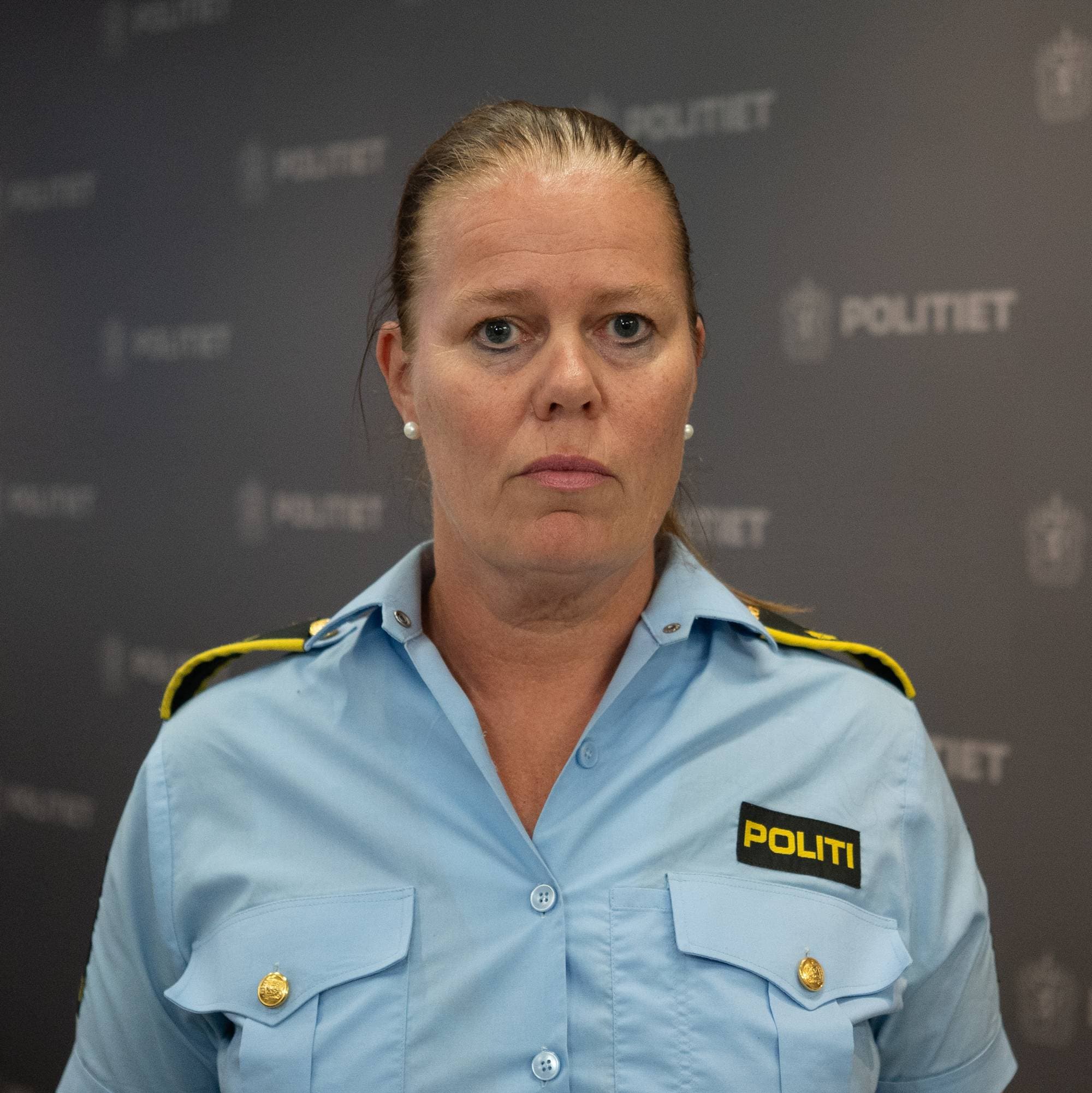 Kvinne i politiuniform ser inn i kamera. Hun har blondt hår samlet i hestehale.