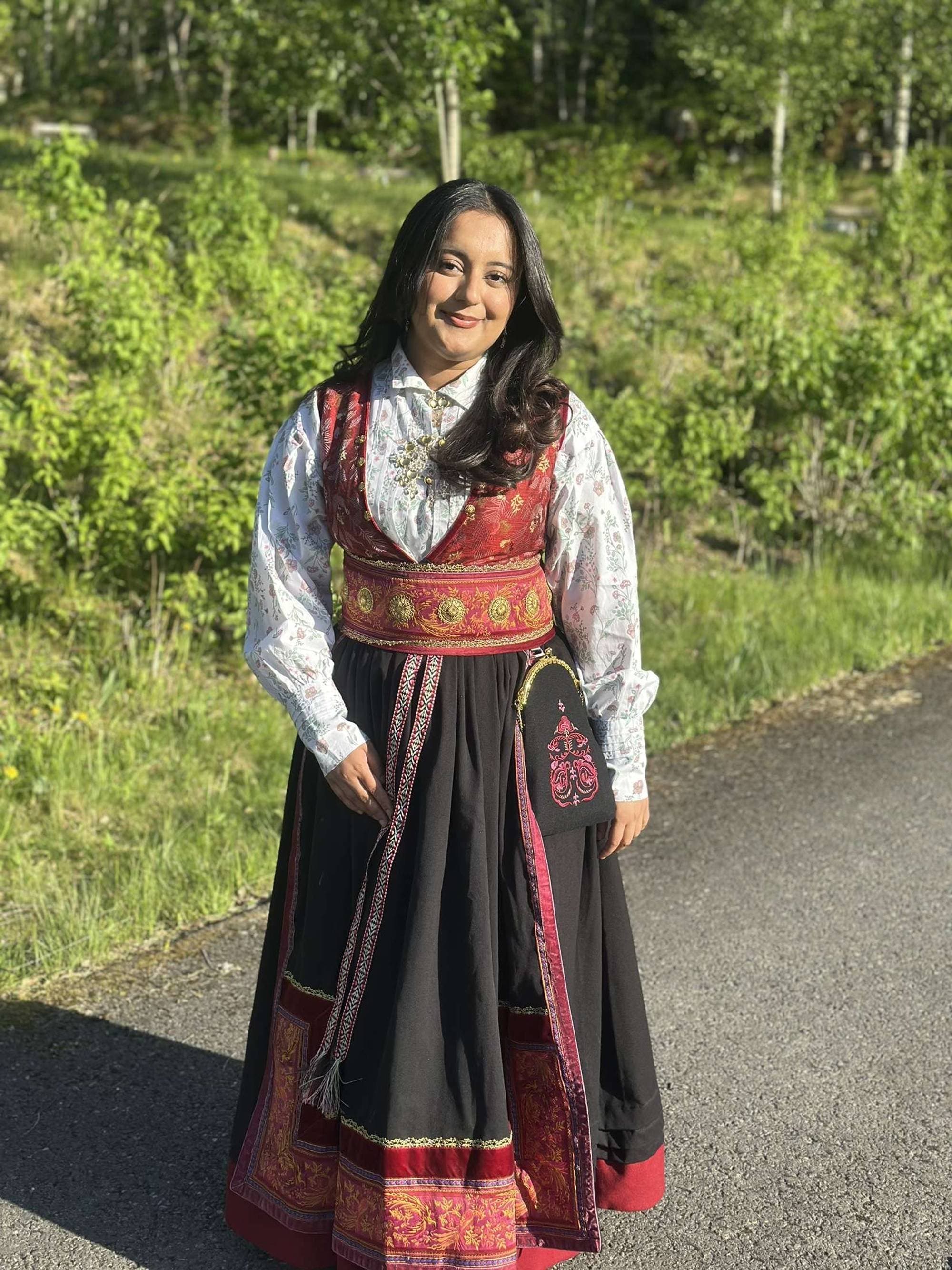 Zahra Nigah Ilyas står med festdrakt ute ved en grønn eng. 