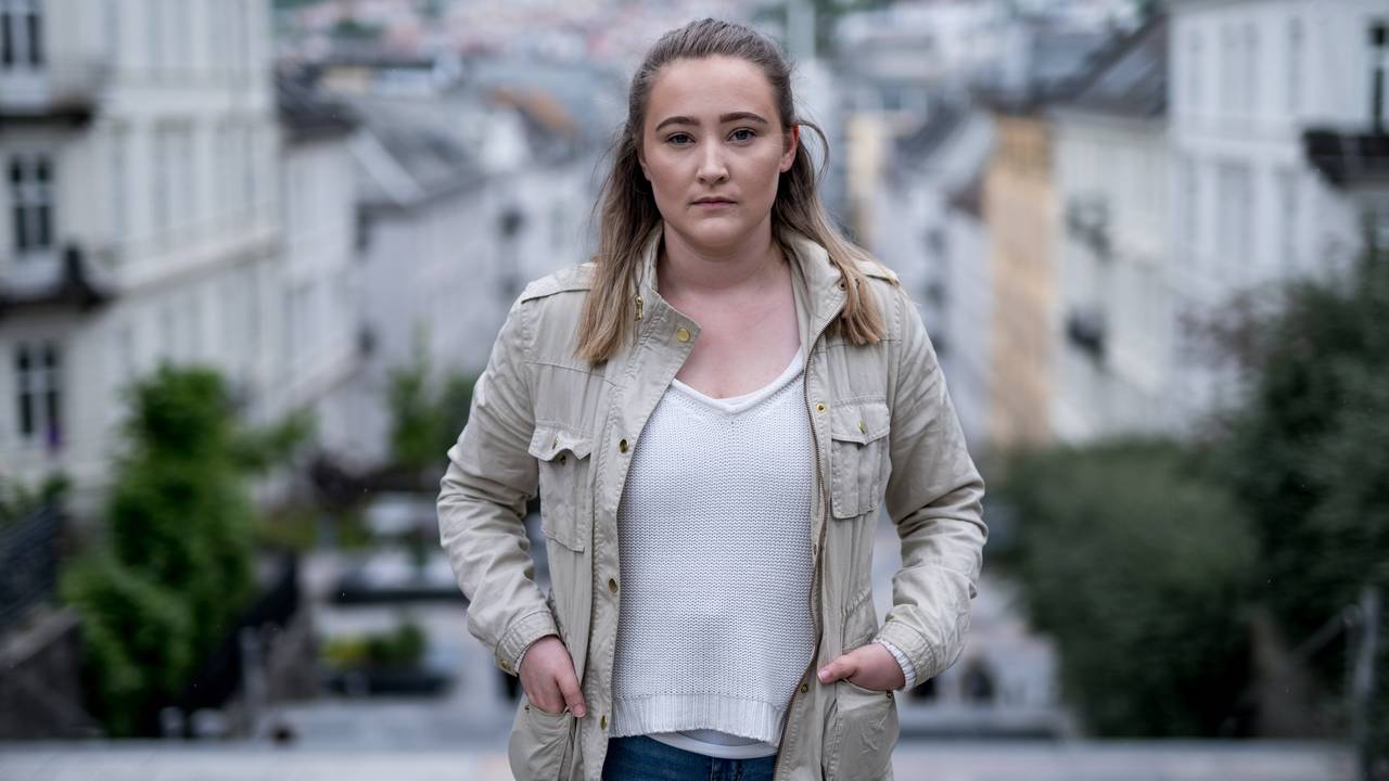 Halvtotalt bilde av Ingebjørg som står i en gate. Bergen by er i bakgrunnen.