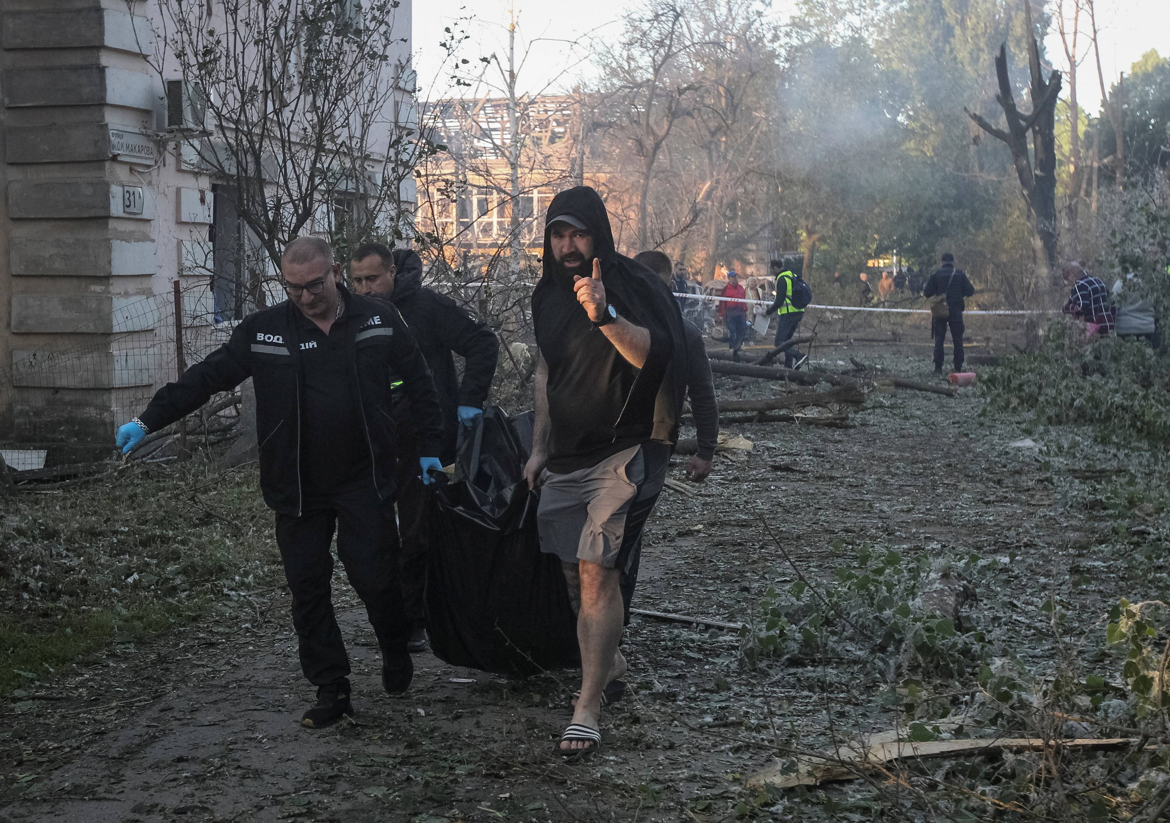 Redningsarbeidere og frivillige bærer bort en død person fra ruinene i Dnipro.