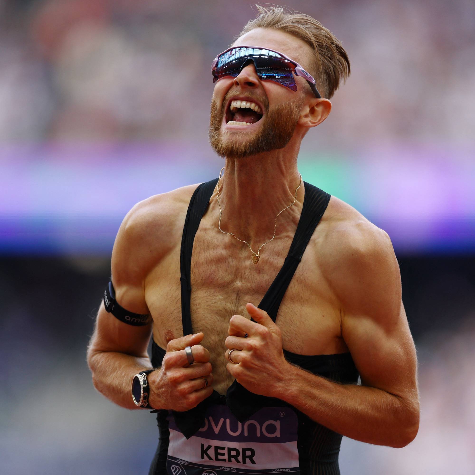 Friidrettsutøver Josh Kerr jubler på en løpebane iført svart singlet og solbriller. (Bildebeskrivelsen er laget av en KI-tjeneste)
