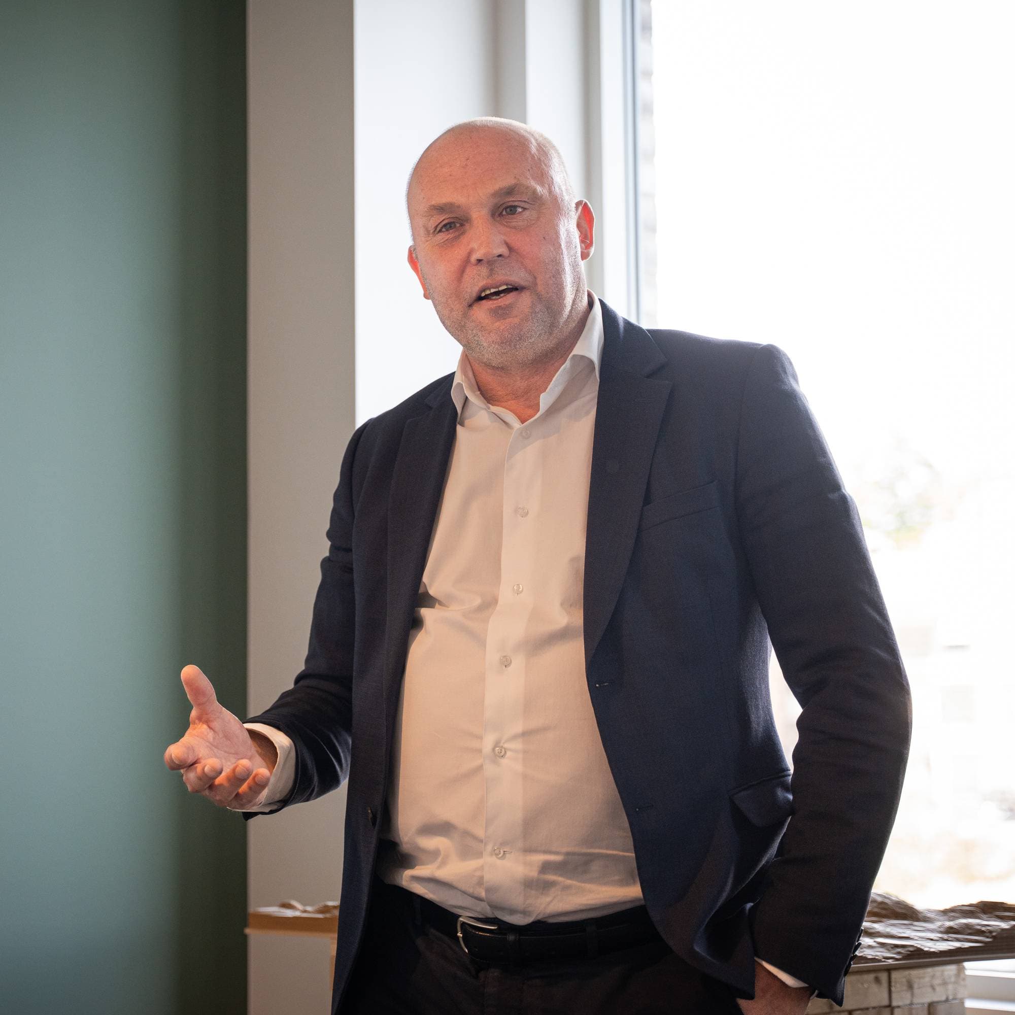 en mann i dress som holder hånden opp