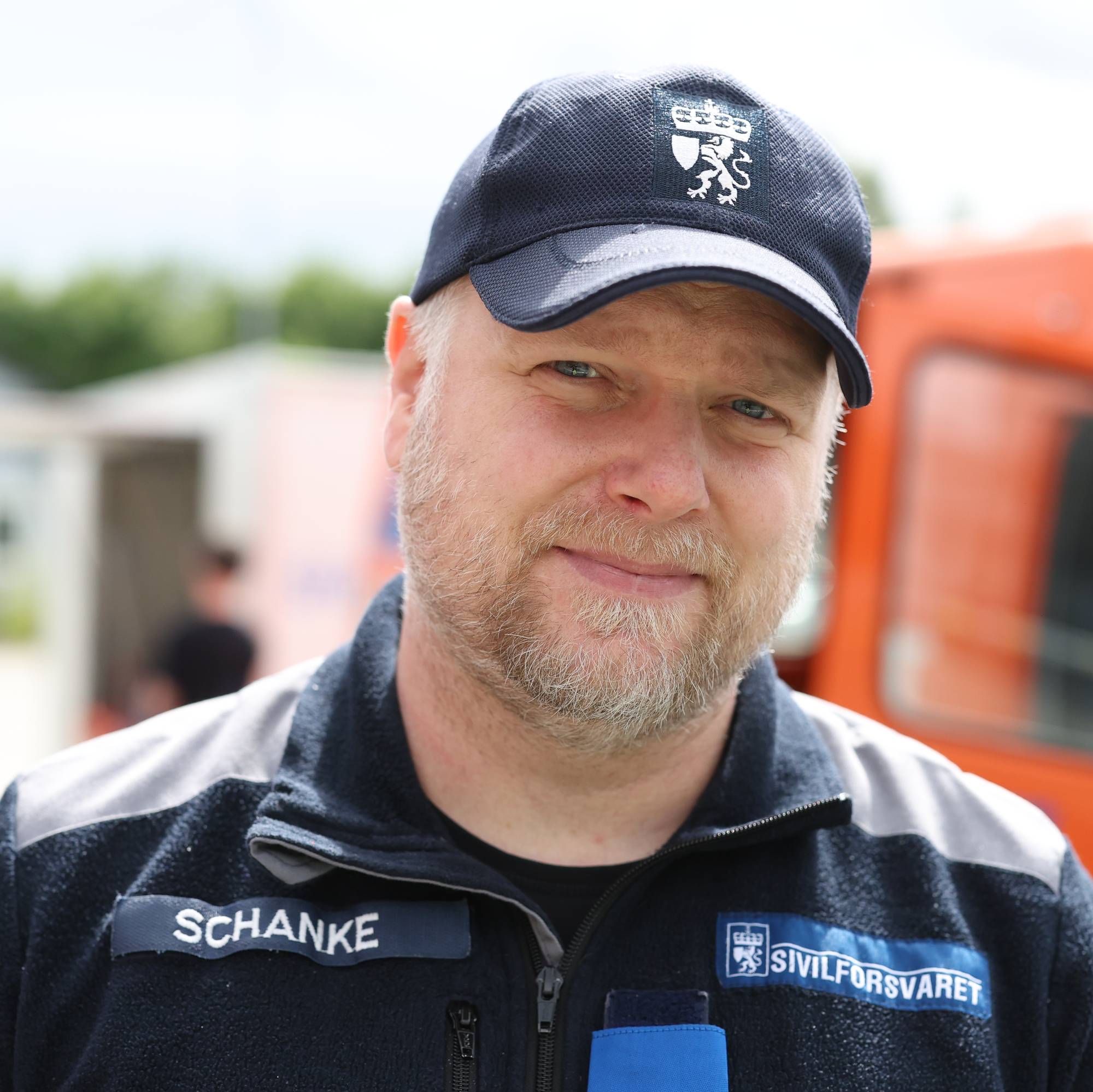 Mann fra Sivilforsvaret med merket Schanke på brystet og caps med Sivilforsvarets emblem. (Bildebeskrivelsen er laget av en KI-tjeneste)