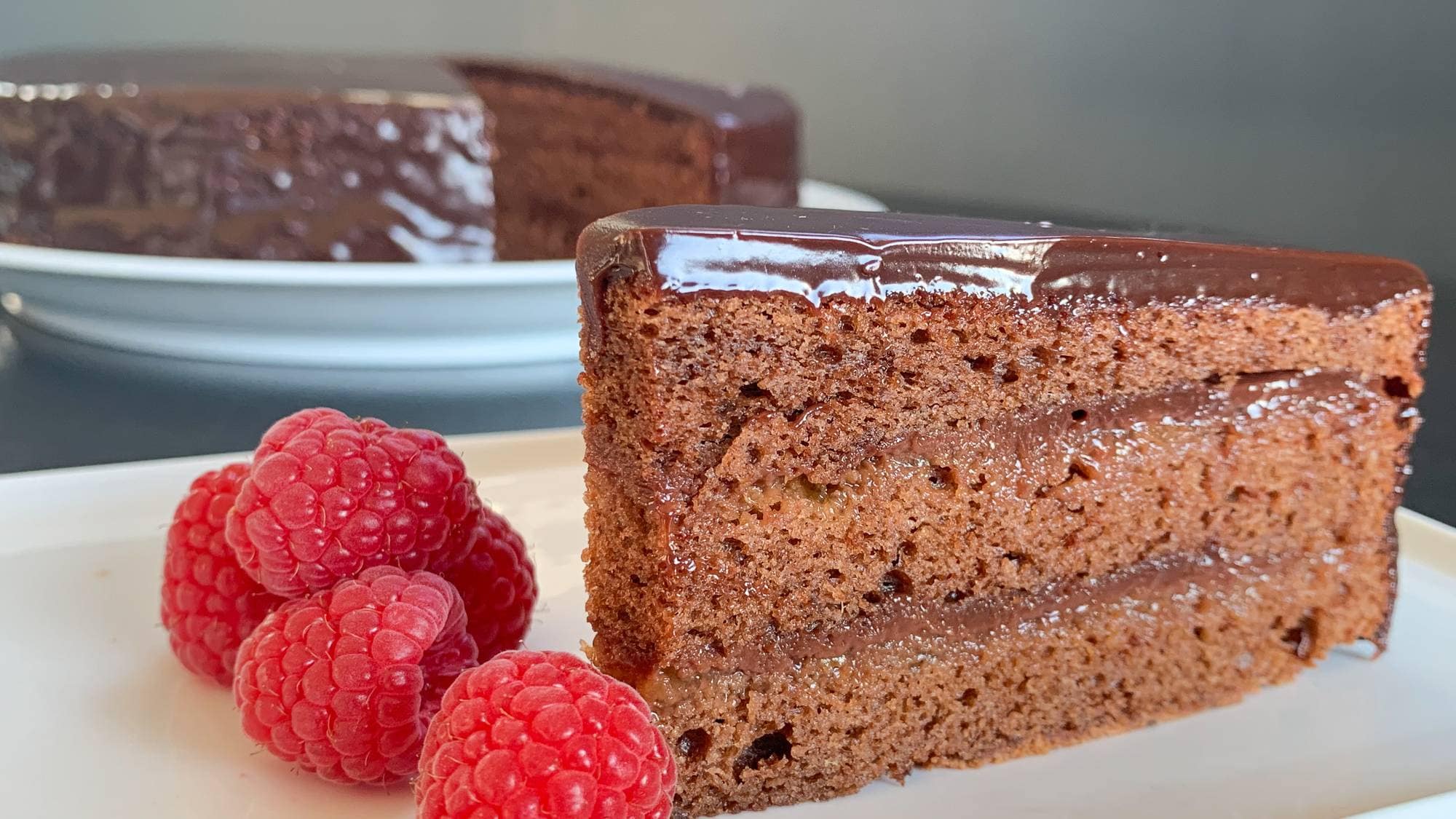 En Skål Med Sachertorte Med Appelsin Og Kanel, Pyntet Med Appelsinskiver Og Kanelstenger