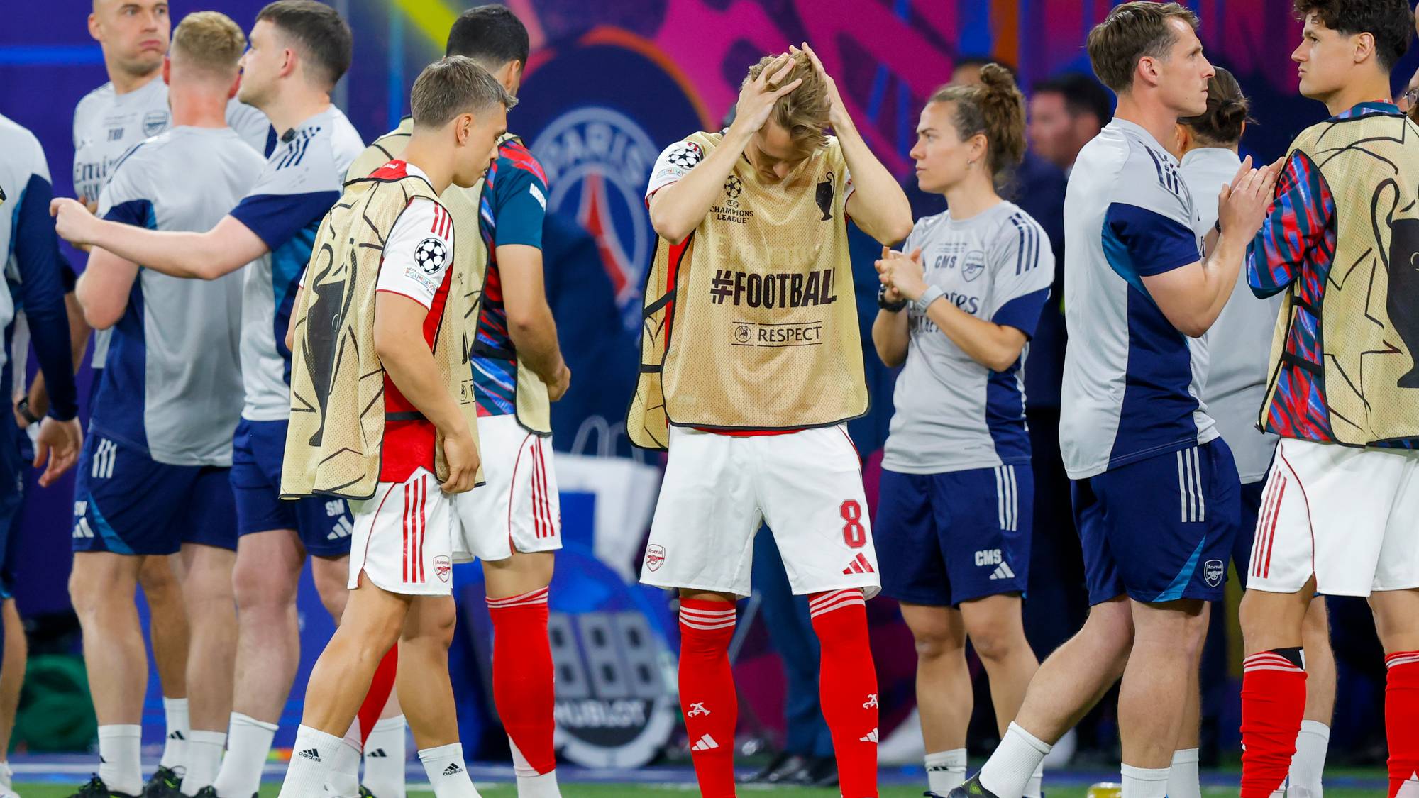 Fotballspillere fra Arsenal står sammen, noen med hodet i hendene. En spiller med draktnummer 8 er i fokus. Andre spillere og trenere er synlige i bakgrunnen. (Bildebeskrivelsen er laget av en KI-tjeneste)