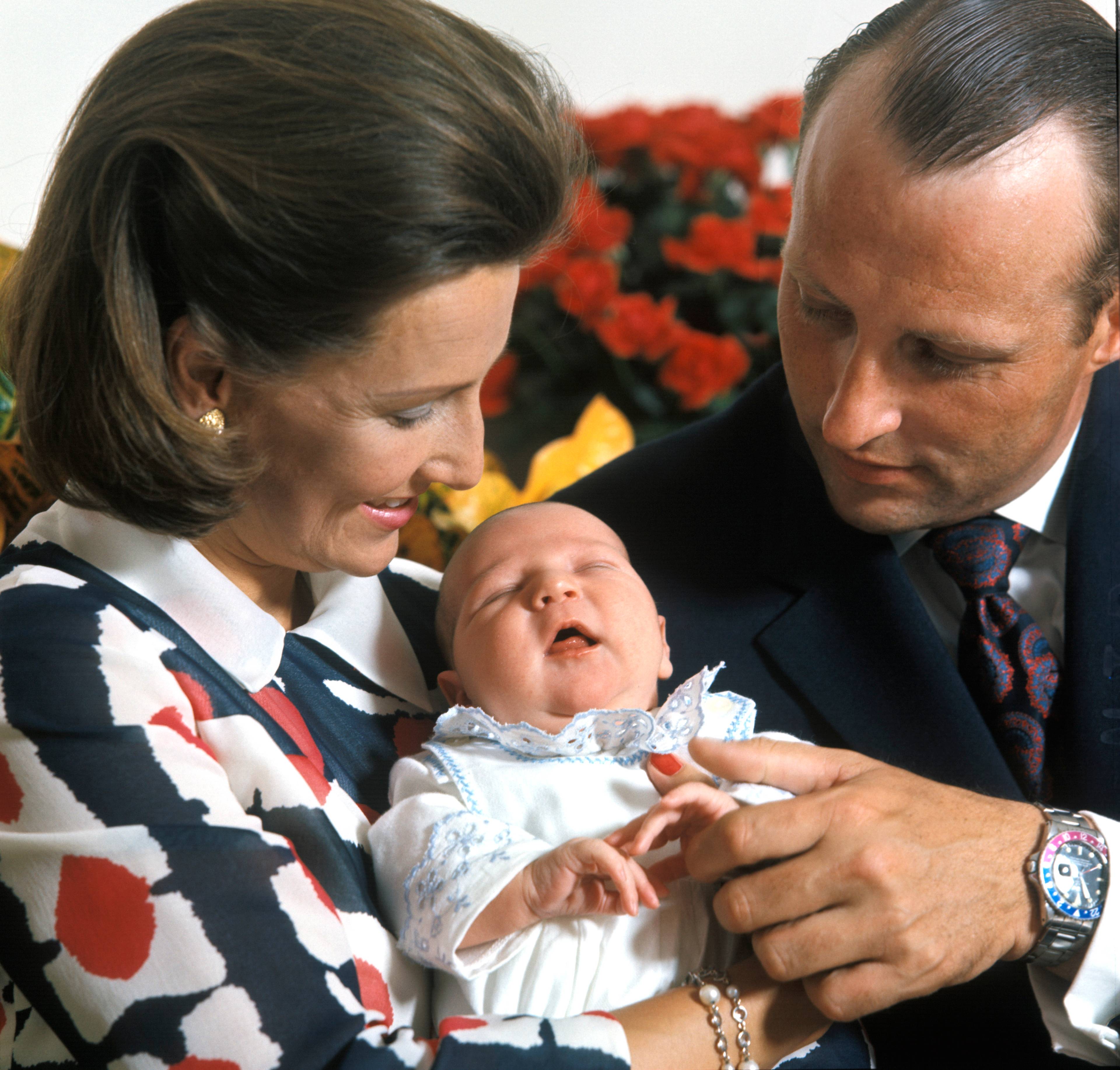 Kronprinsesse Sonja holder den nyfødte prins Haakon Magnus i armene, mens kronprins Harald holder den lille gutten i hånden. De er fotografert på Rikshospitalet i Oslo få dager etter fødselen.