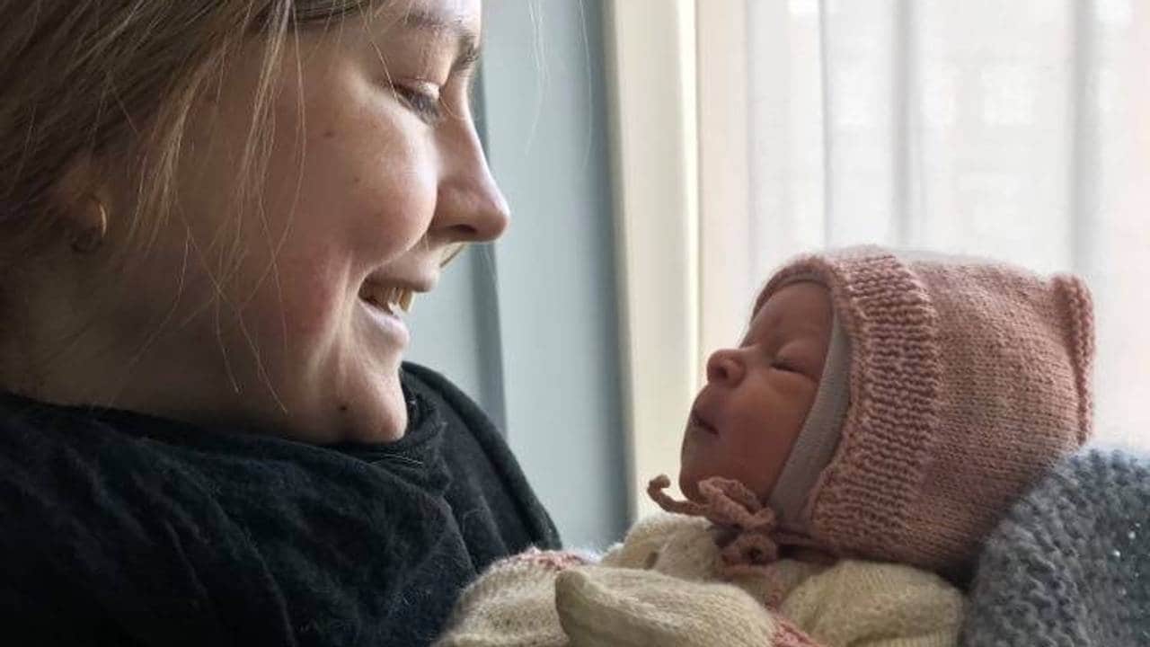 Marie ser på nyfødt Pauline i ullklær