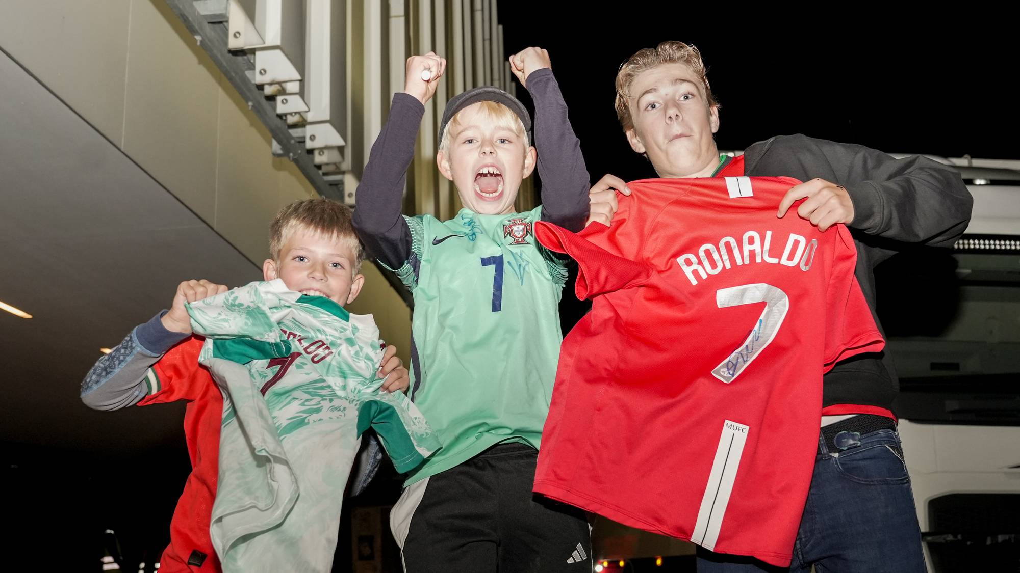 Tre gutter viser frem fotballdrakter med Ronaldo-navn. En av draktene har en signatur. (Bildebeskrivelsen er laget av en KI-tjeneste)